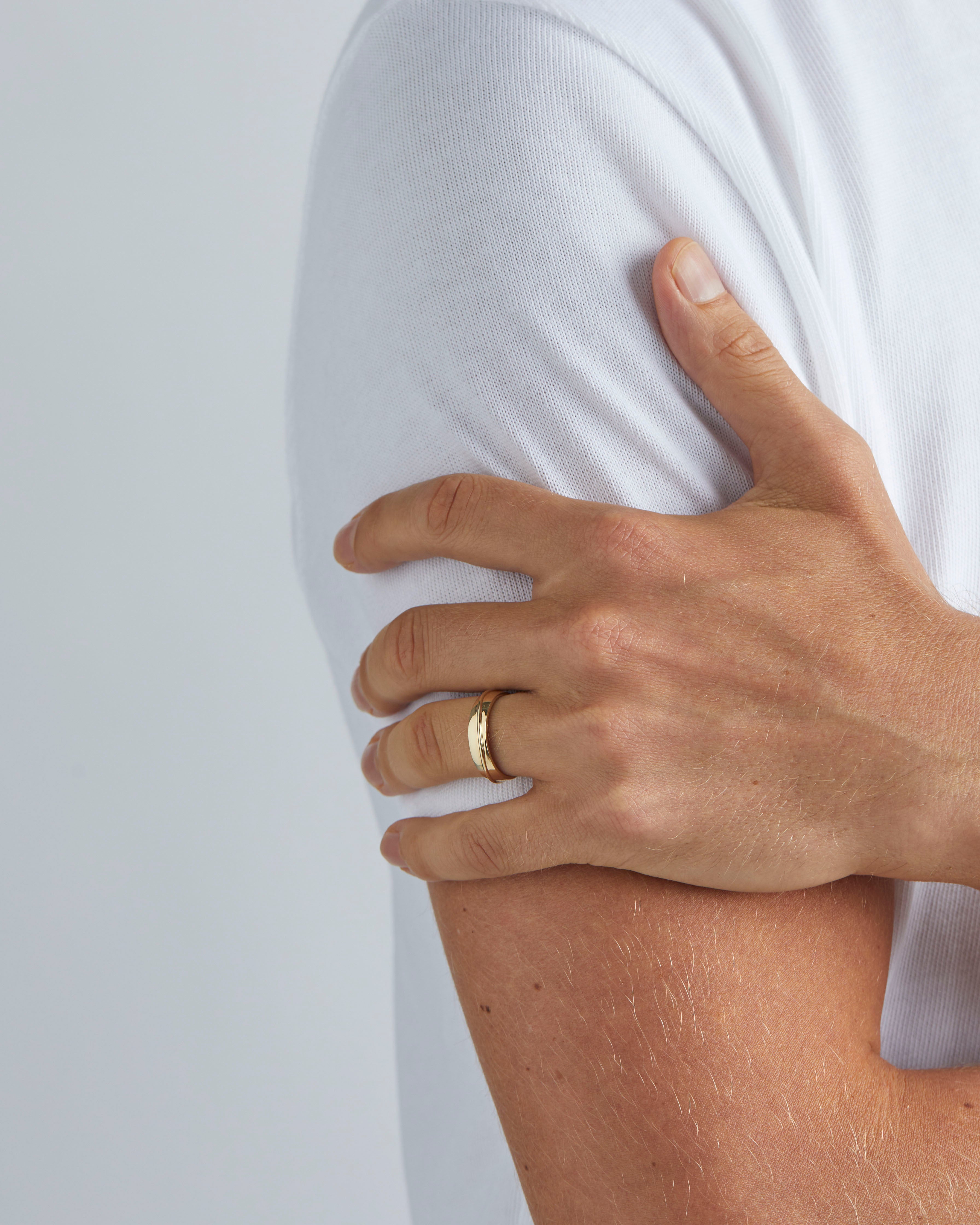 A model wears our 5mm surge wedding ring in yellow gold