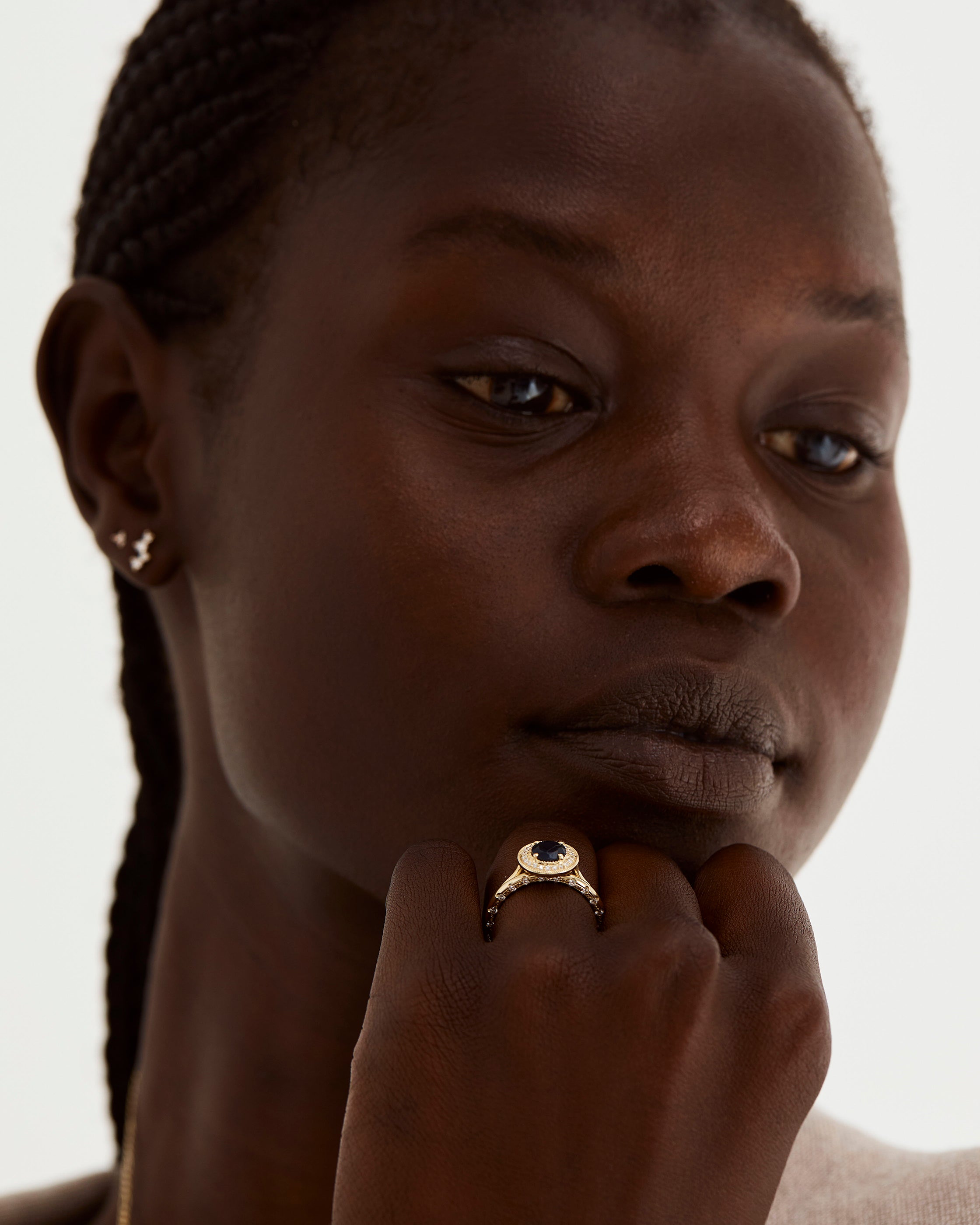 Model wears a sapphire halo engagement ring, stacked with out cascade side profile band, where diamonds can be seen only from the side.