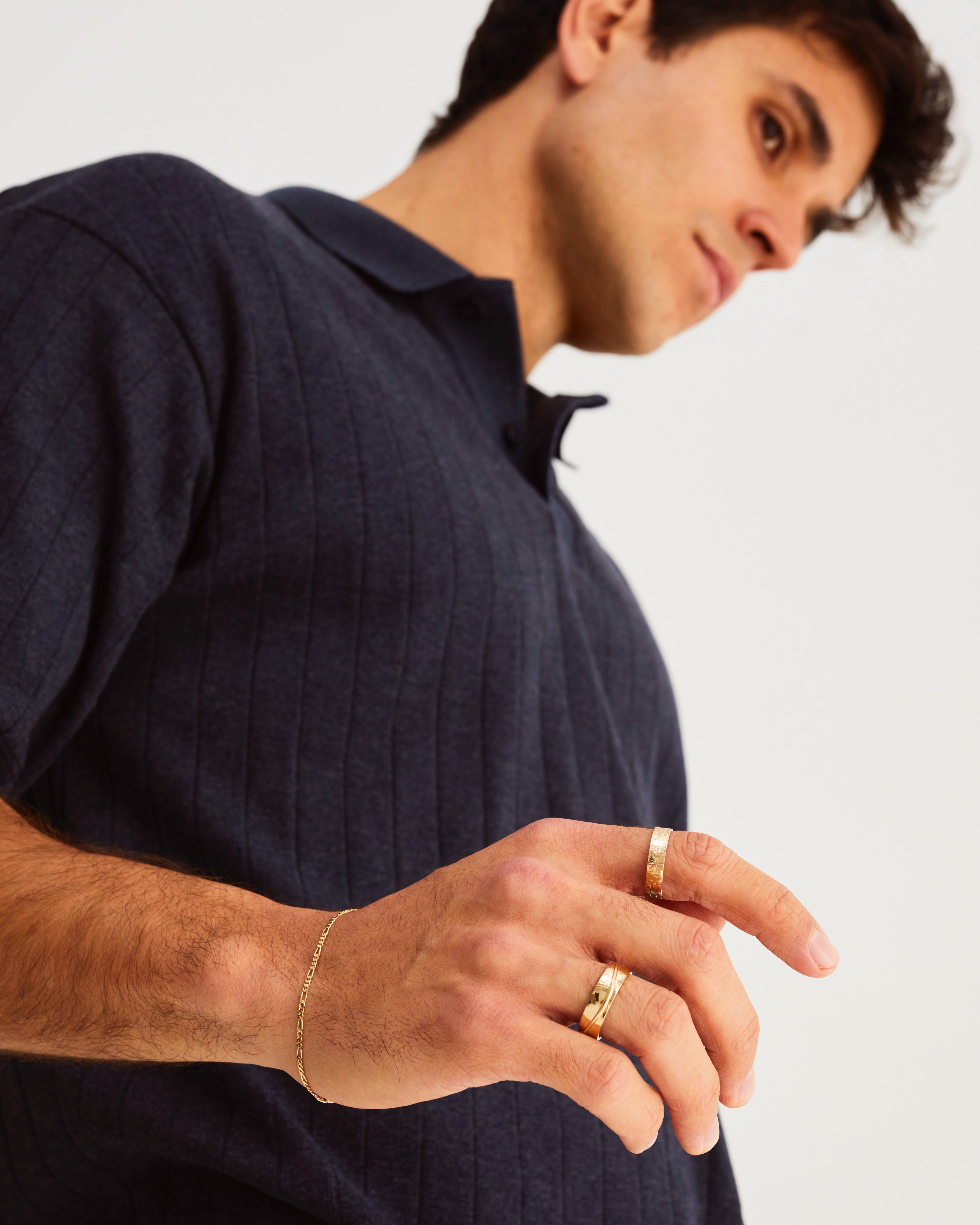 A man wears the 6mm Surge Wedding Band and naum stacking ring in yellow gold
