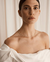 Photo of model wearing white wedding dress wearing the demi Ember diamond necklace
