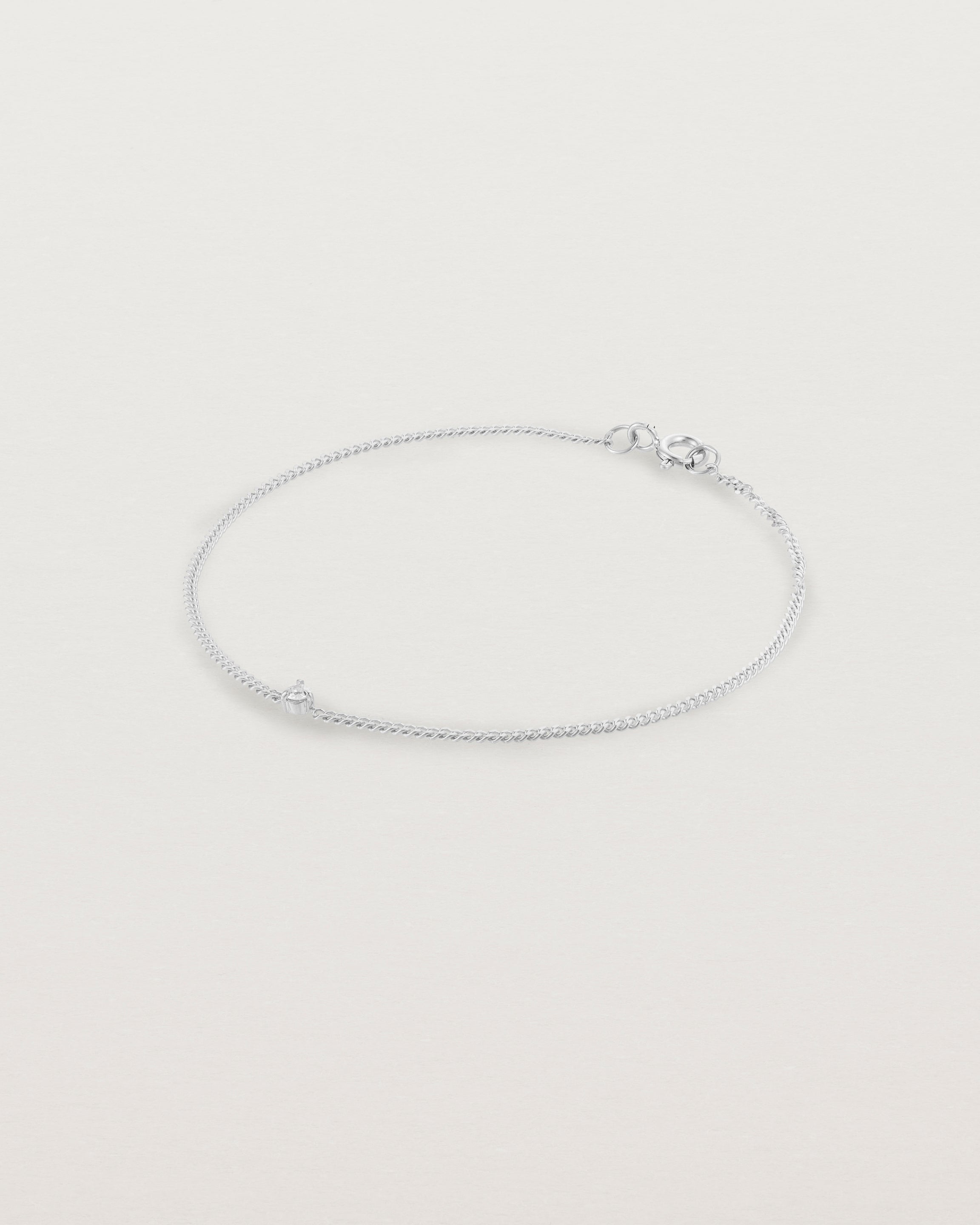 A white gold chain bracelet featuring a single white old cut diamond
