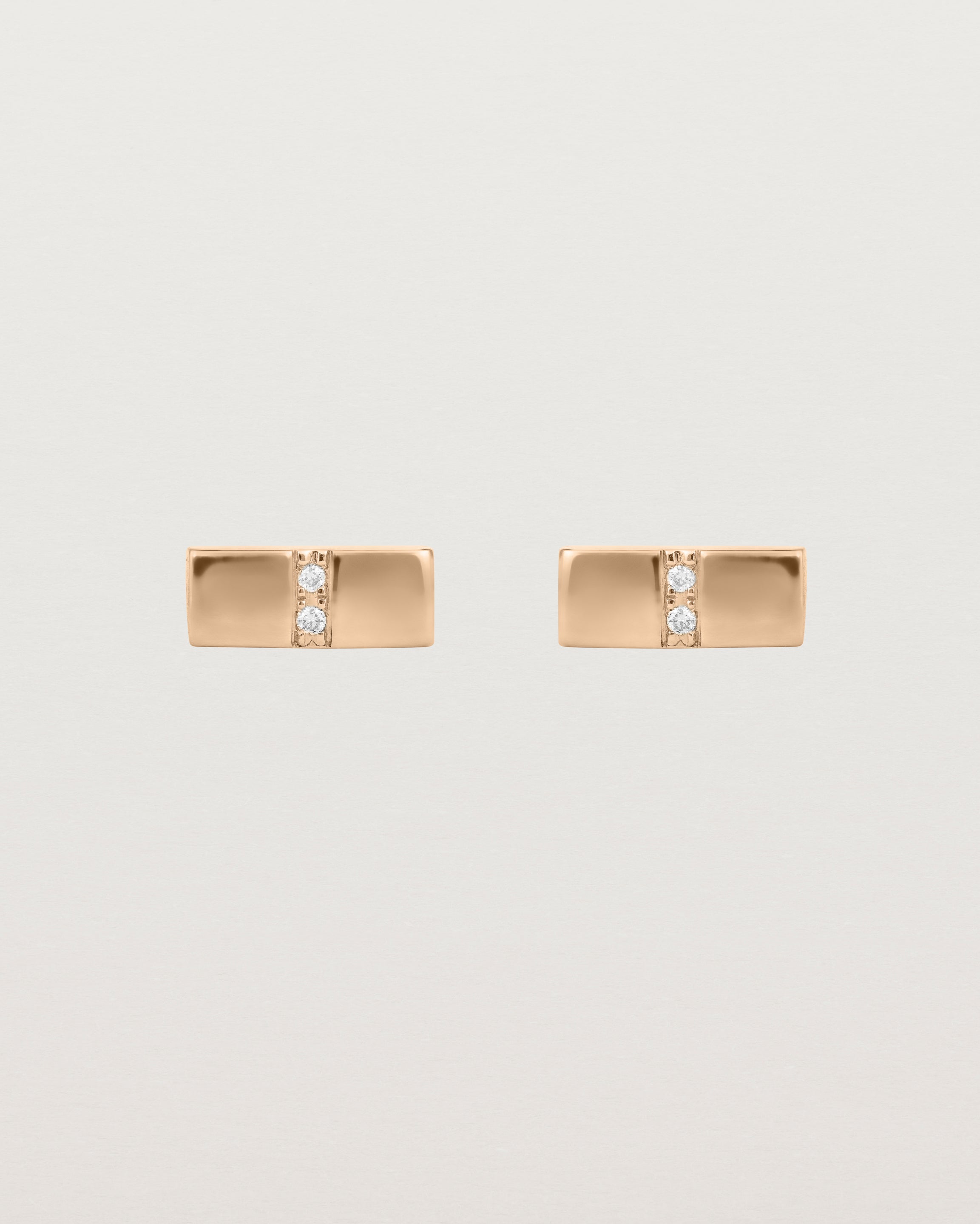 A pair of small rose gold rectangle studs featuring two white diamonds set in the centre