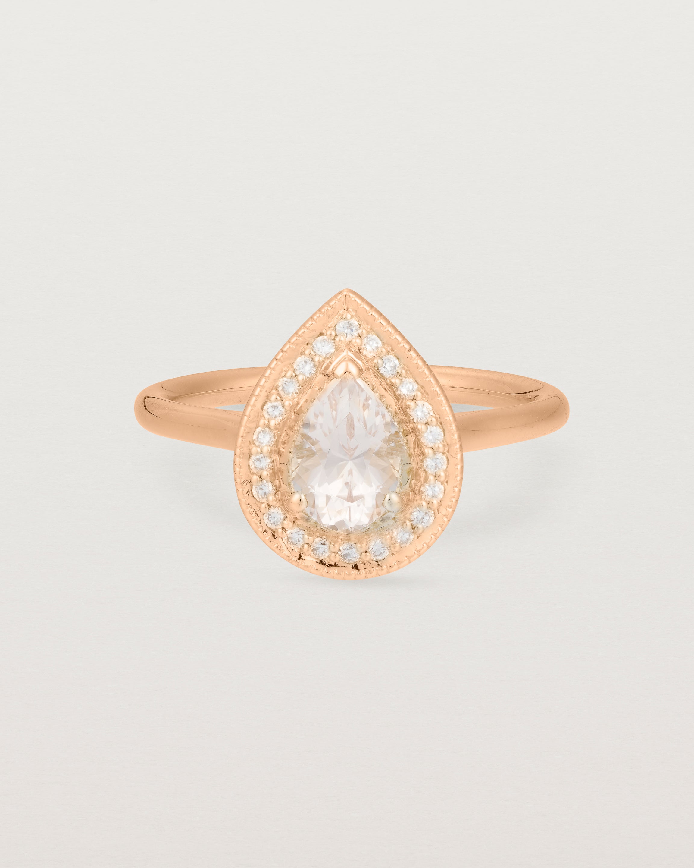 Front view pear halo ring featuring a pear cut pale pink morganite and a halo of white diamonds in rose gold