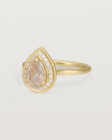 Side view pear halo ring featuring a pear cut rutilated quartz stone and a halo of white diamonds in yellow gold