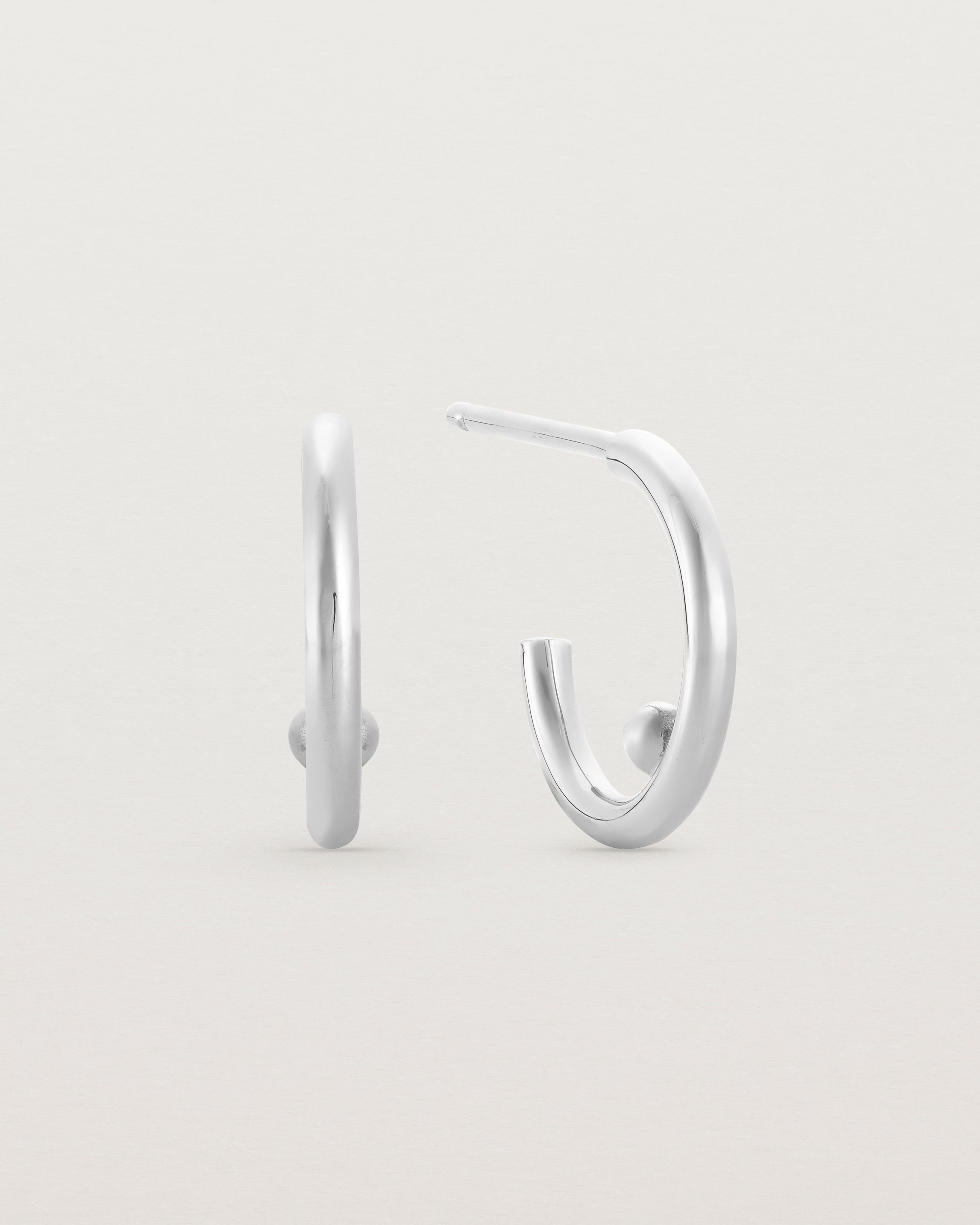 A small pair of silver open hoops with a silver ball in the centre