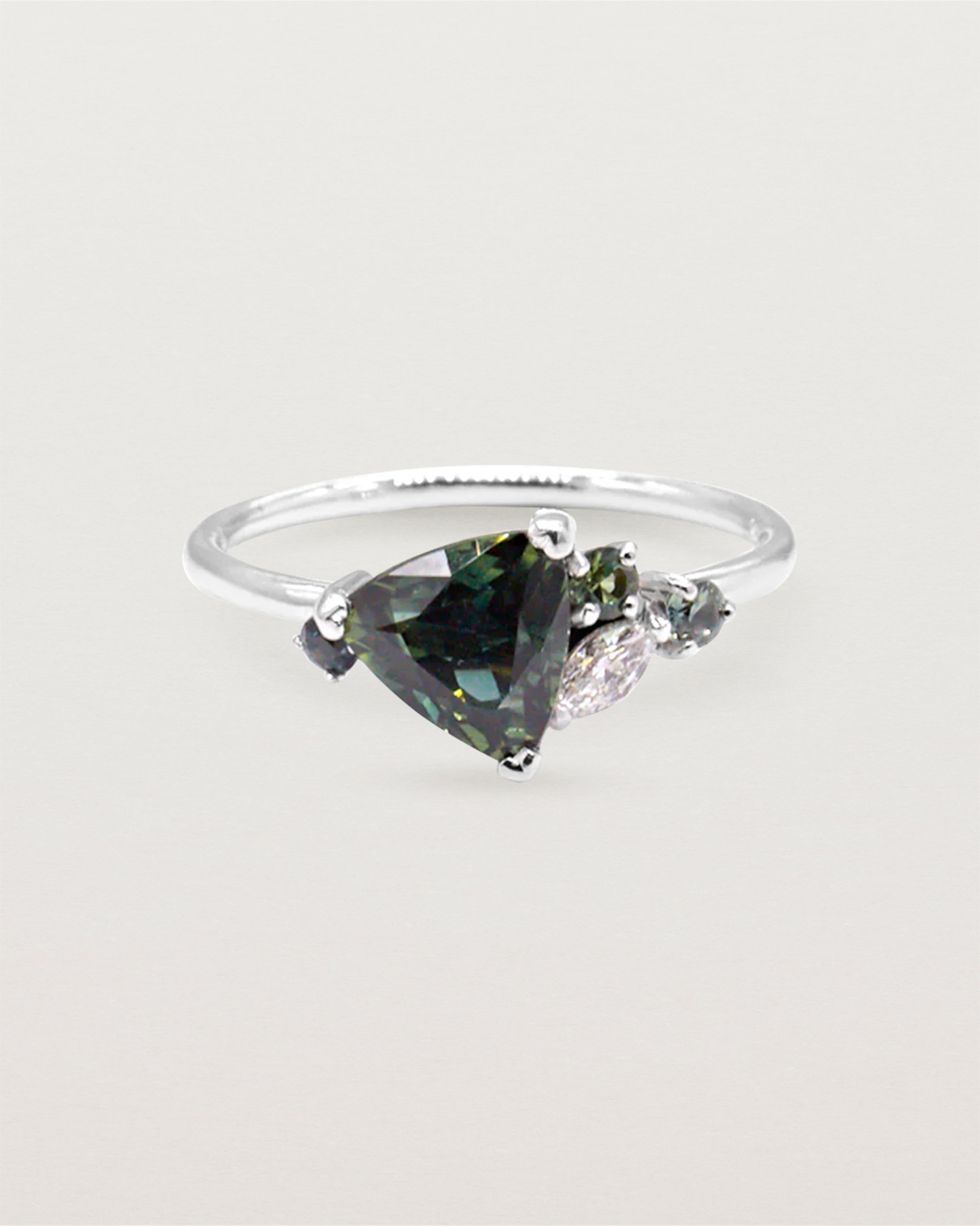 A distinctive cluster, featuring an iridescent trillion cut sapphire and crafted in white gold