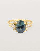 A large oval teal sapphire adorned with white diamond clusters, crafted in yellow gold