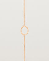 A rose gold chain bracelet featuring a circle set with small white diamonds