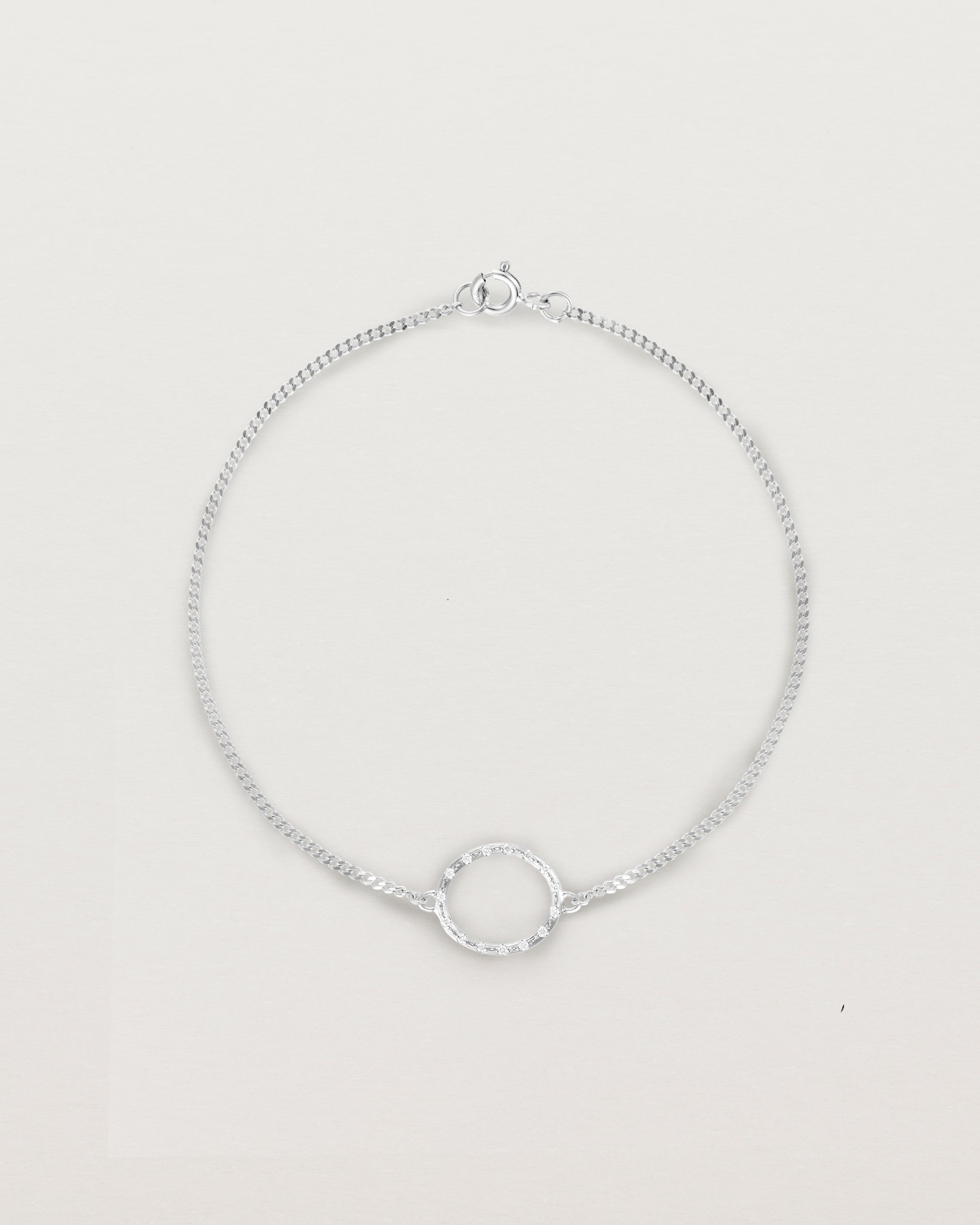 A white gold chain bracelet featuring a circle set with small white diamonds
