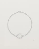 A white gold chain bracelet featuring a circle set with small white diamonds