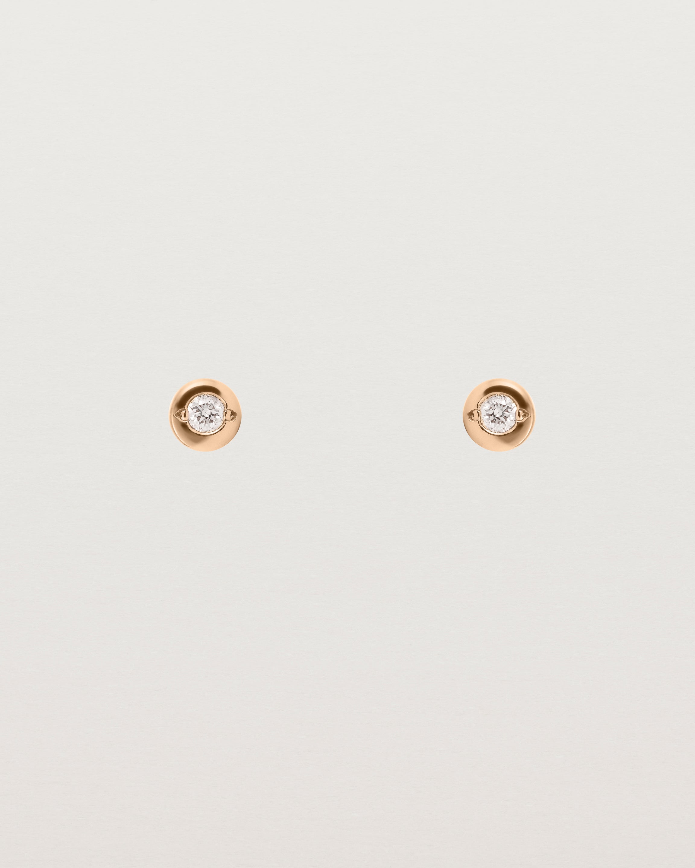 A small white circular rose gold stud featuring a white diamond