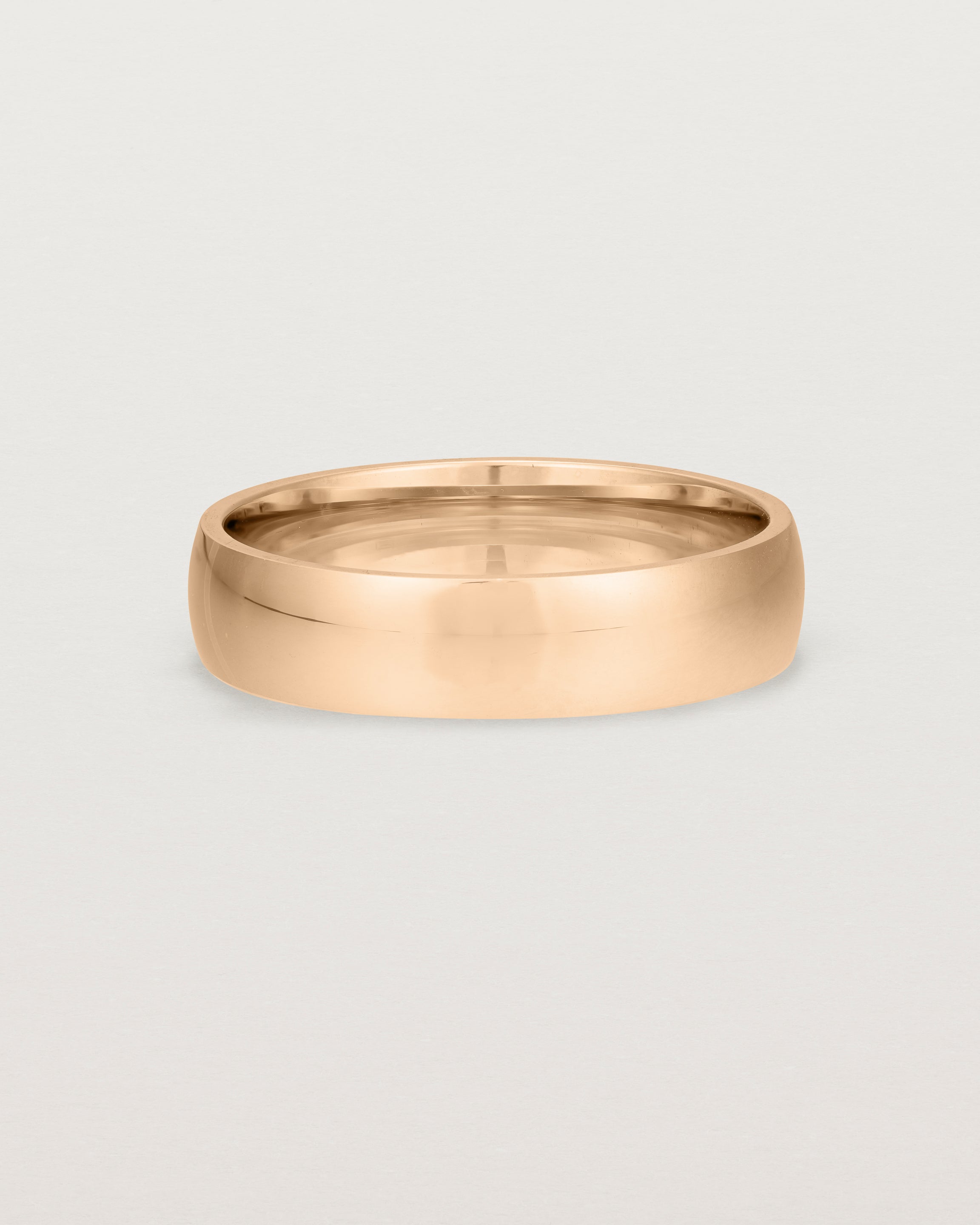 The front view of a 5mm wide heavy wedding ring in rose gold.
