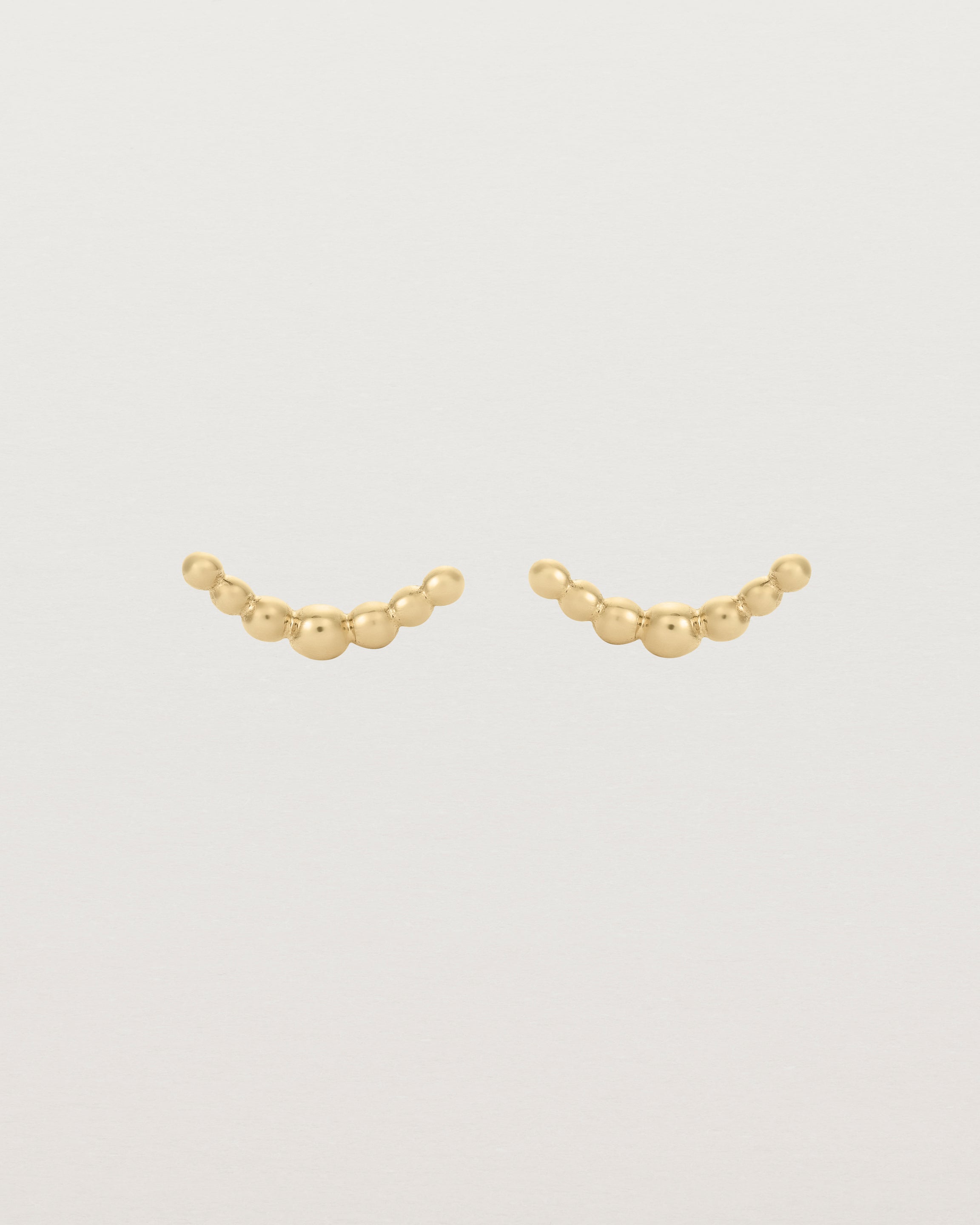 A pair of yellow gold studs featuring an arc of round metal balls