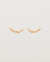 A pair of rose gold studs featuring an arc of round metal balls