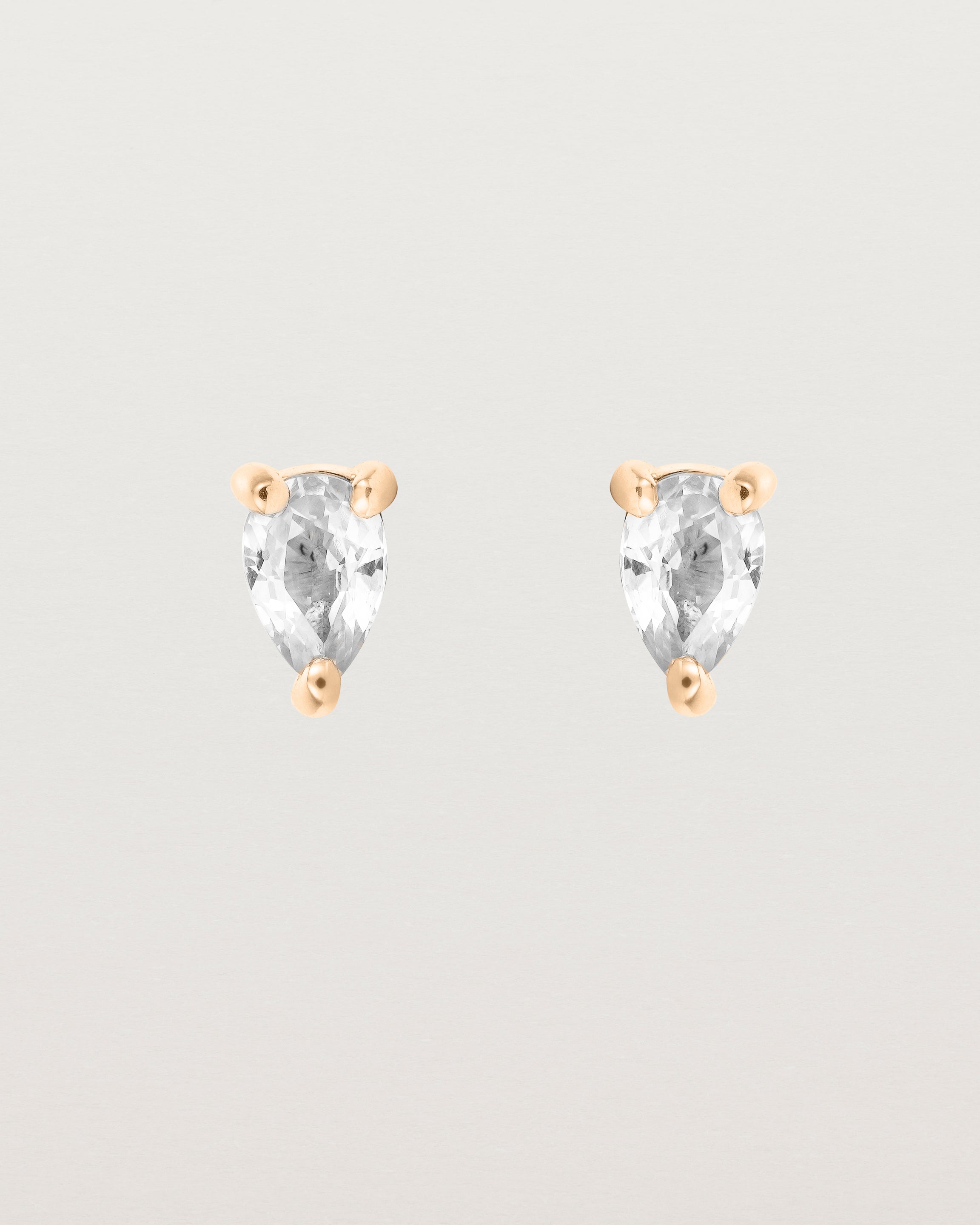 a pair of rose gold studs featuring a pear cut diamond