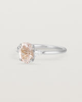The side view of an oval morganite adorned with two white diamonds either side, featuring a sweeping setting and crafted in white gold