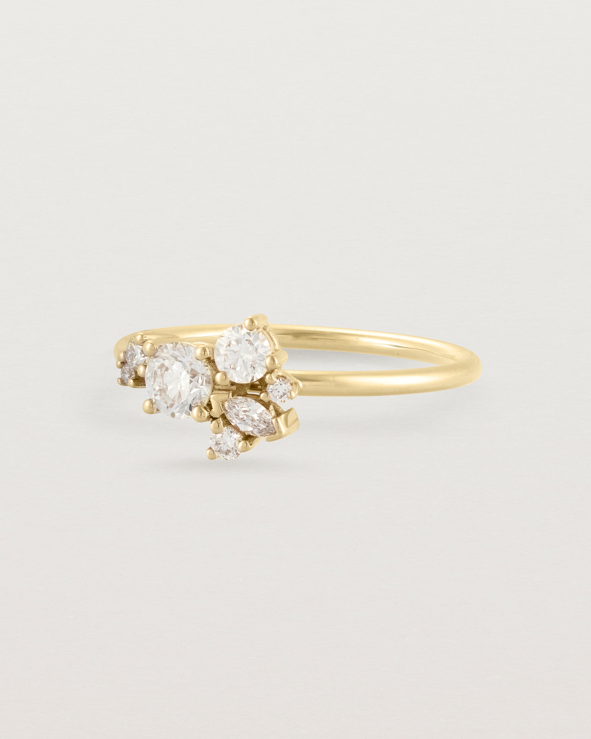Side view of a white diamond cluster ring in yellow gold