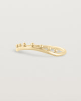 The side view of a gentle arc ring with dot detailing along the top of the arc, crafted in yellow gold