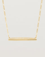 close up of Ellipse necklace with a yellow gold bar hanging from a chain in yellow gold