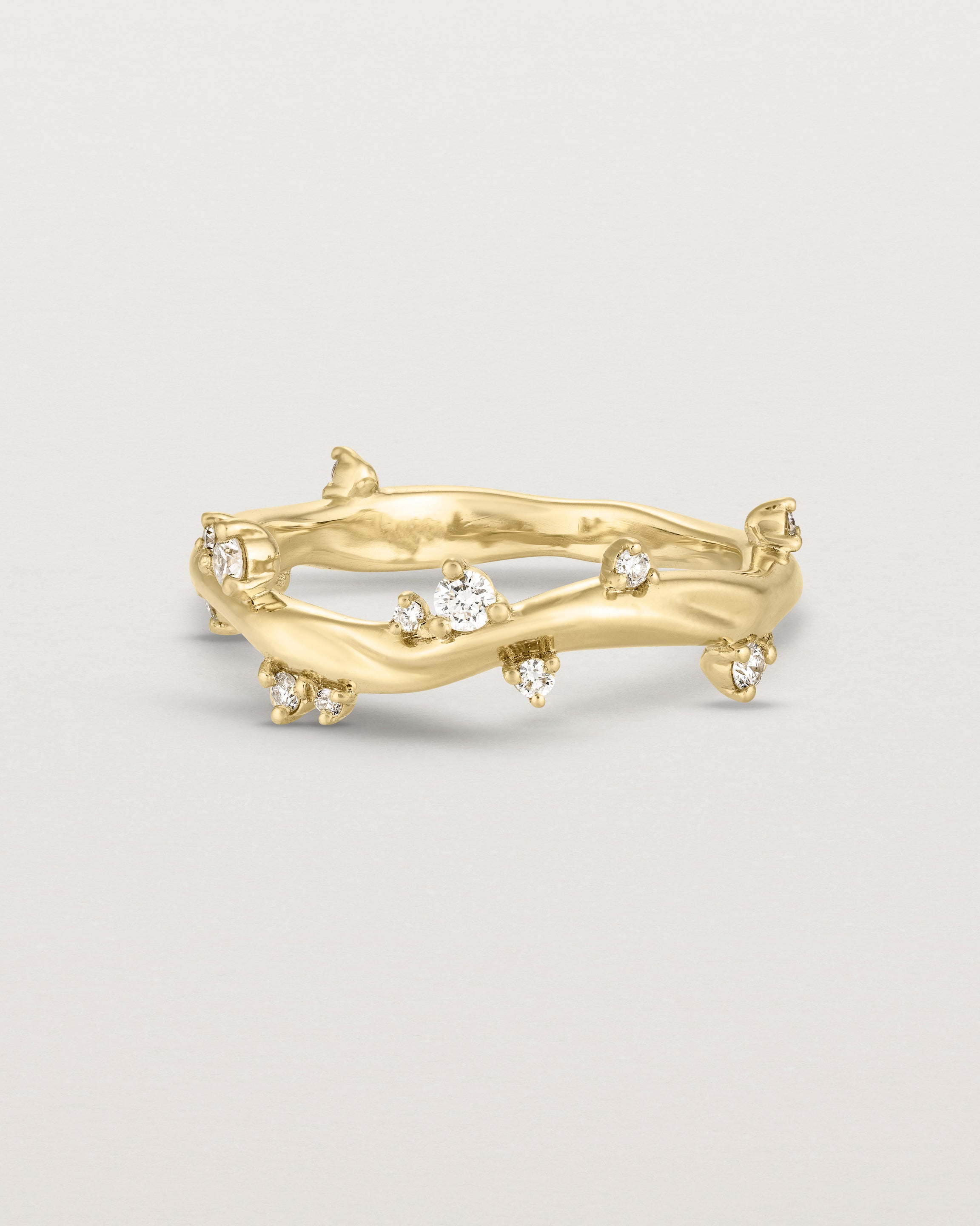 Product photo of the yellow gold Ember ring with white diamonds scattered around the band.