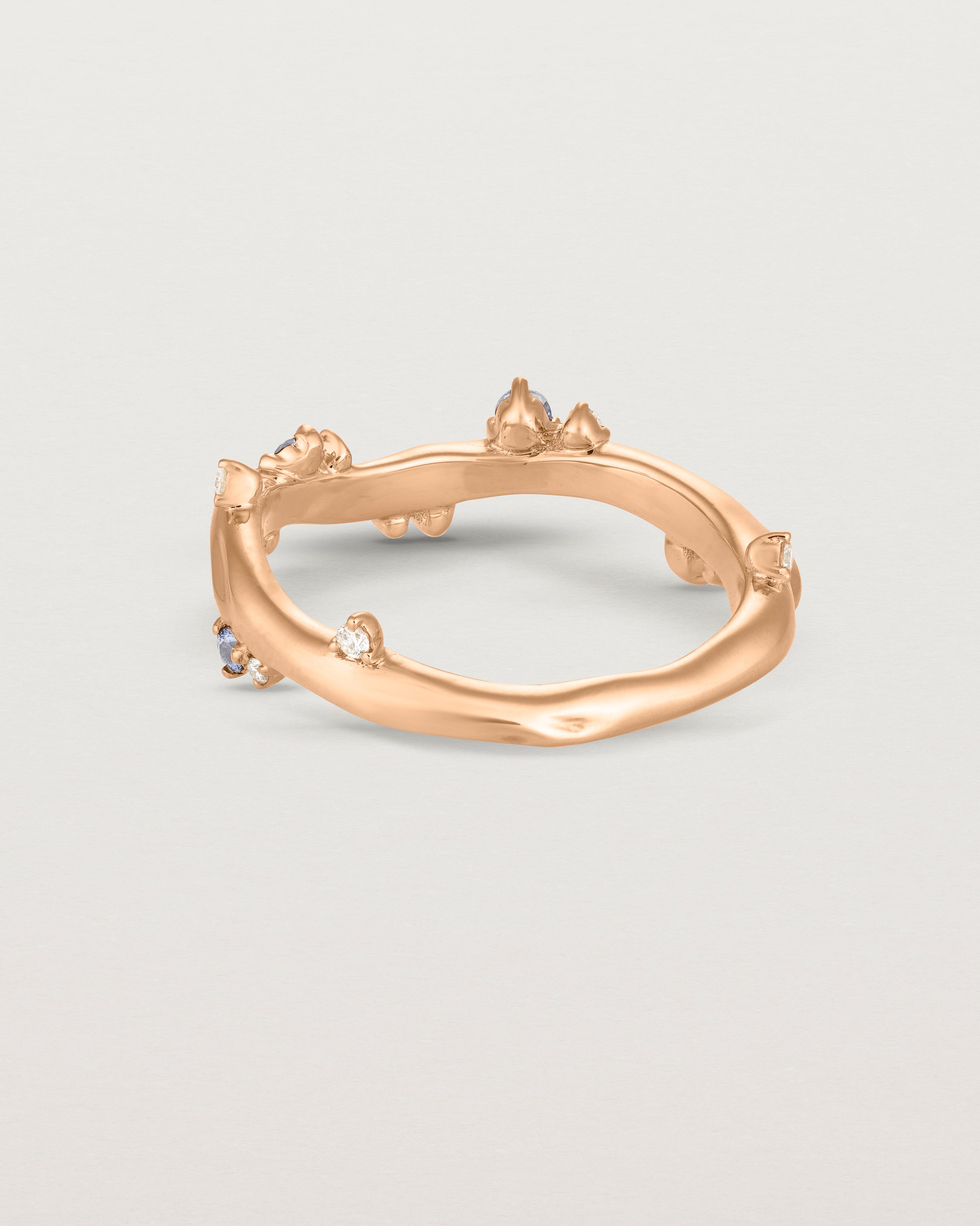 Back image of the Ember ring in rose gold featuring a scattering of white diamonds and blue sapphires.