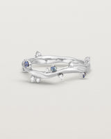 Front image of the Ember ring in white gold featuring a scattering of white diamonds and blue sapphires.