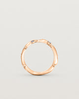Standing image of the Ember ring in rose gold featuring a scattering of white diamonds and blue sapphires.
