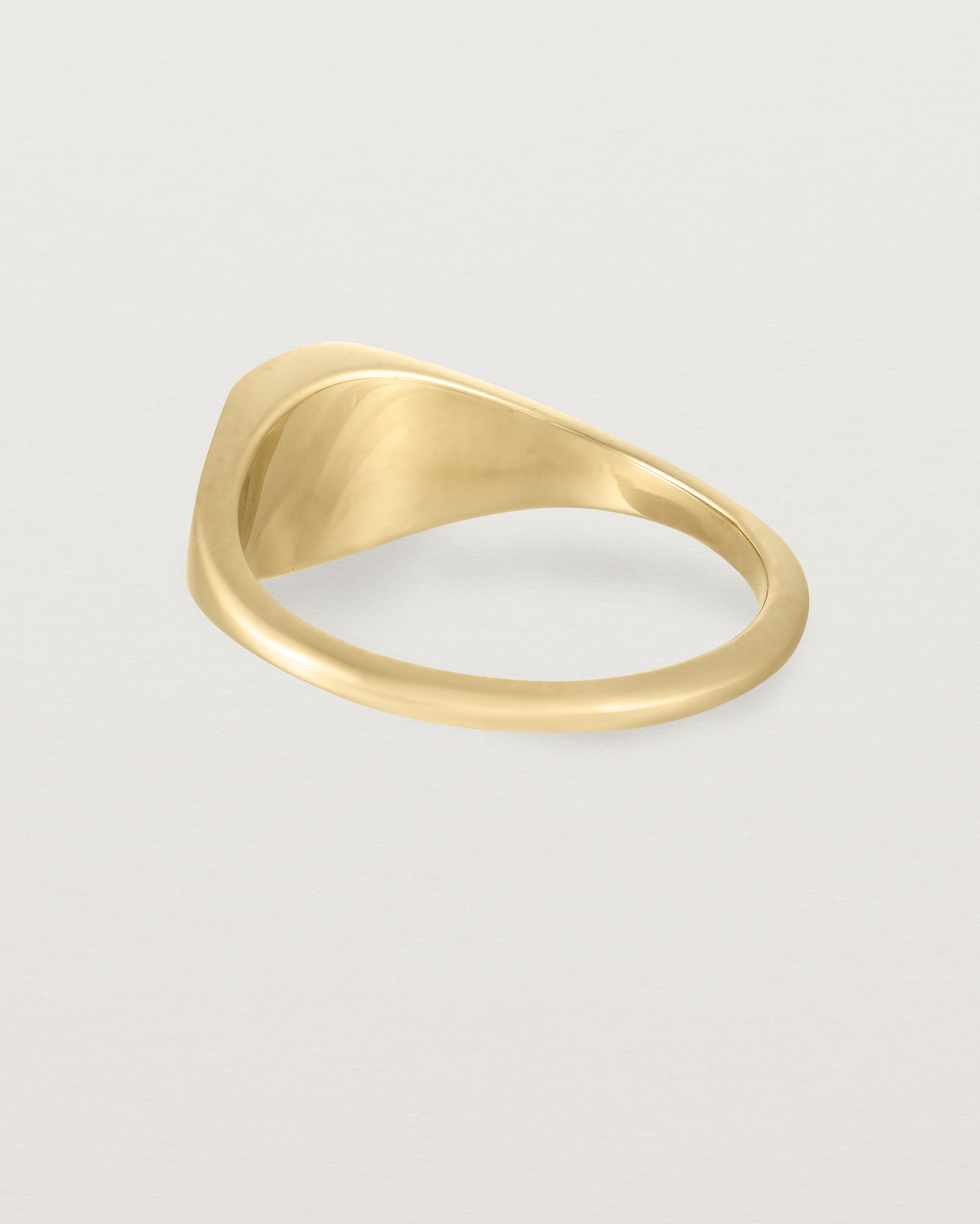 Angled view of a simple signet with an elongated rectangular face in yellow gold