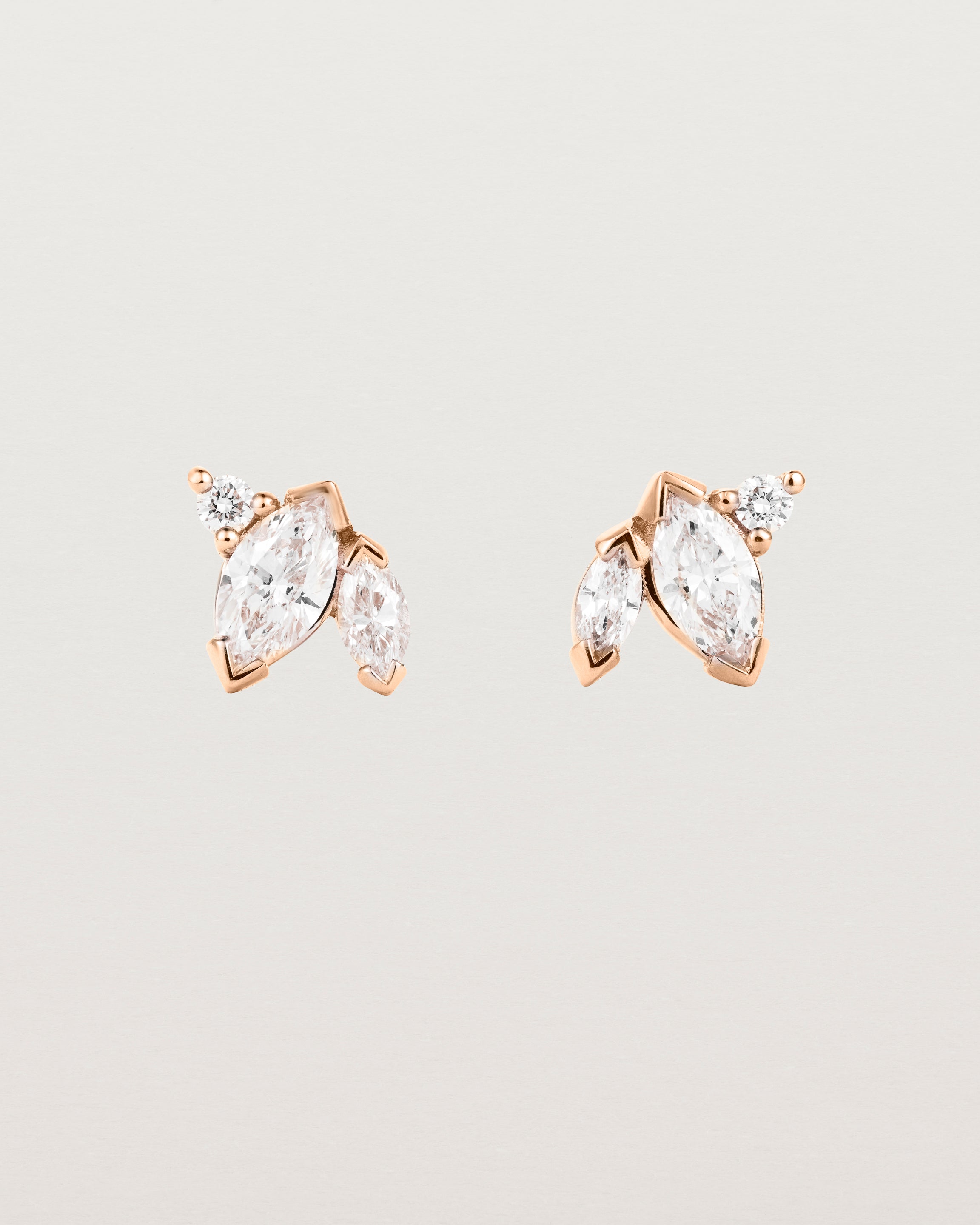A pair of rose gold studs featuring two marquise and one round diamond