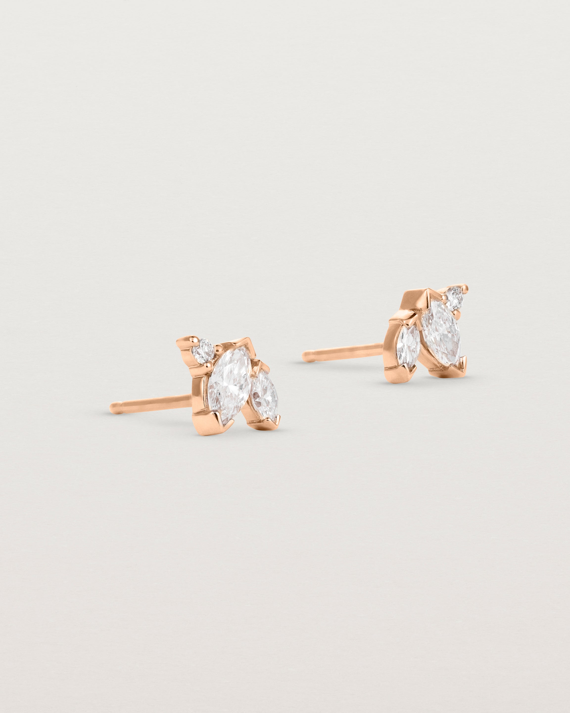 A pair of rose gold studs featuring two marquise and one round diamond