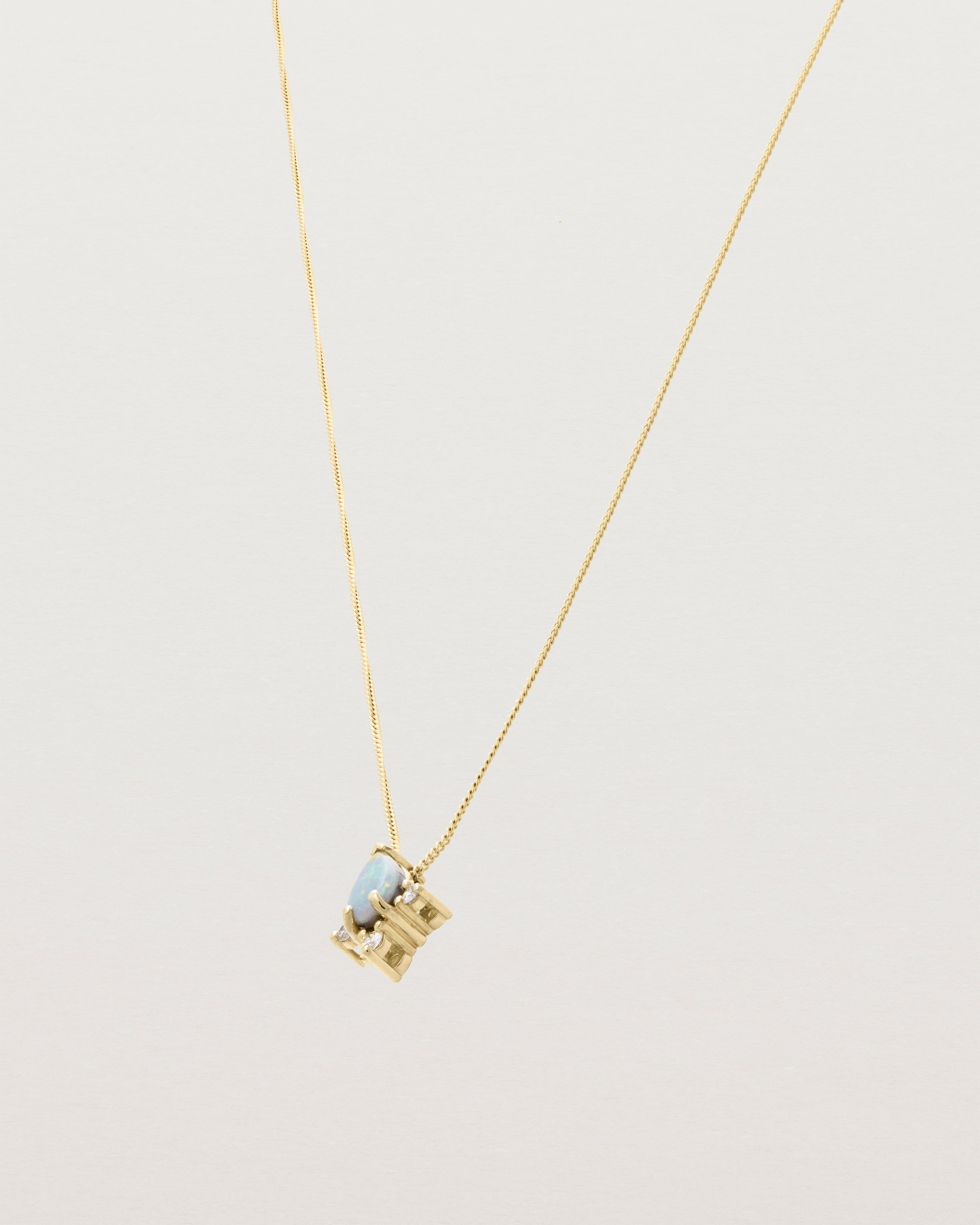 A yellow gold necklace featuring a blue opal stone with three small diamonds