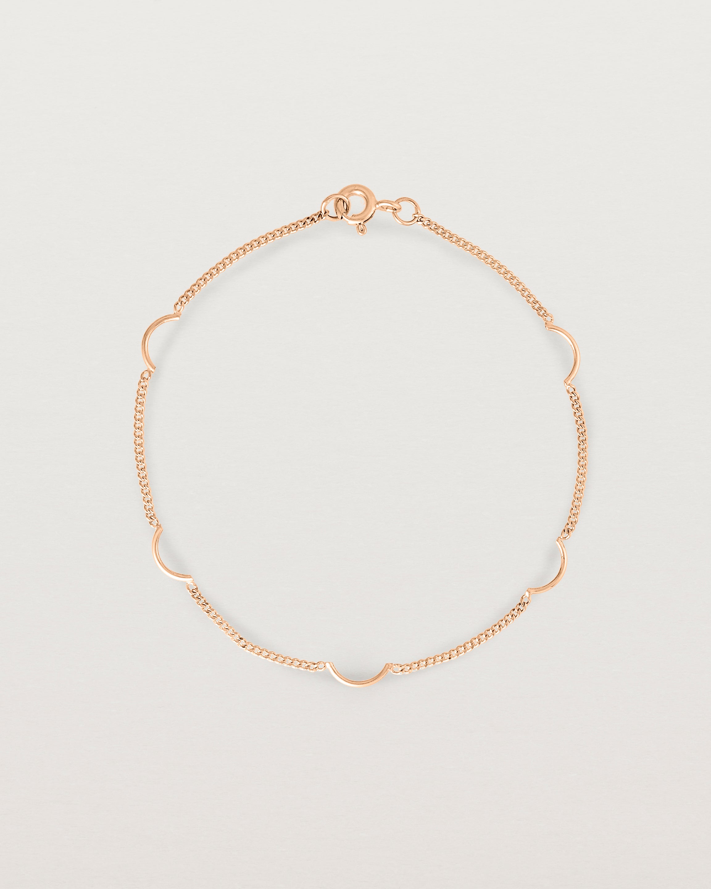 A rose gold chain bracelet with five gold arcs