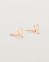 A small pair of rose gold studs shaped like a tear drop