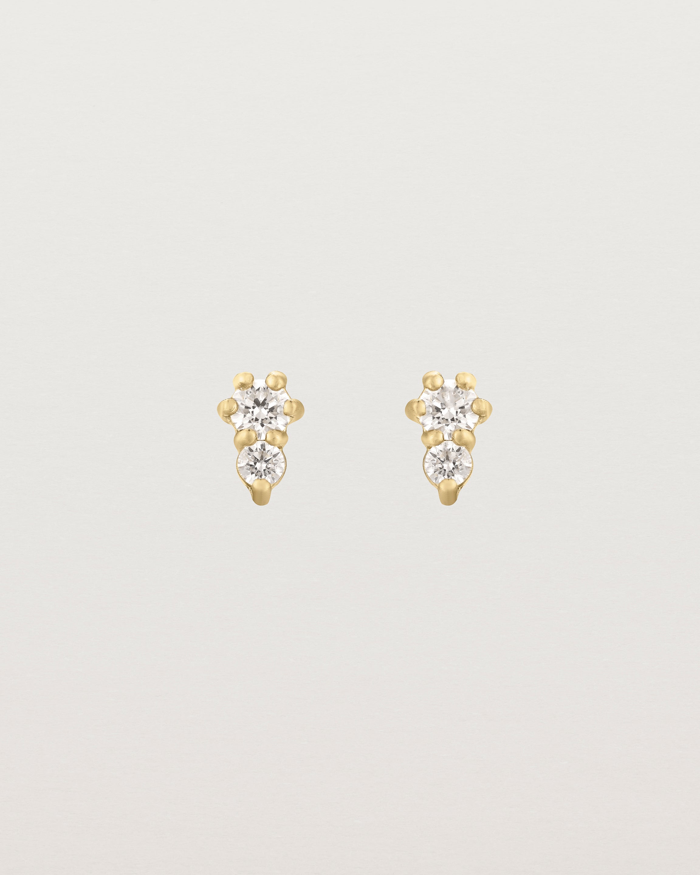 Front facing deep etched image of a pair of yellow gold earrings with diamonds.