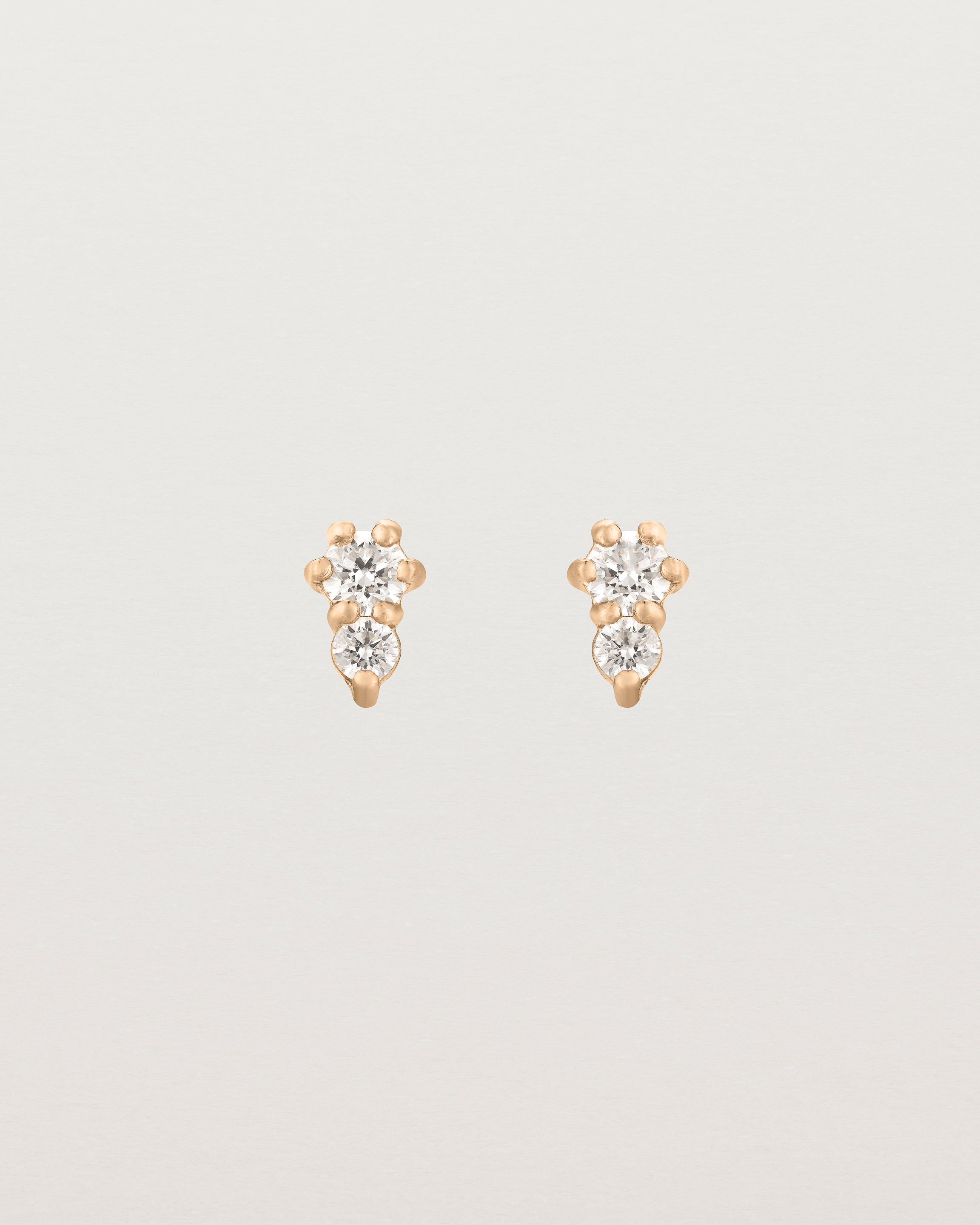 Front facing deep etched image of a pair of rose gold earrings with diamonds.