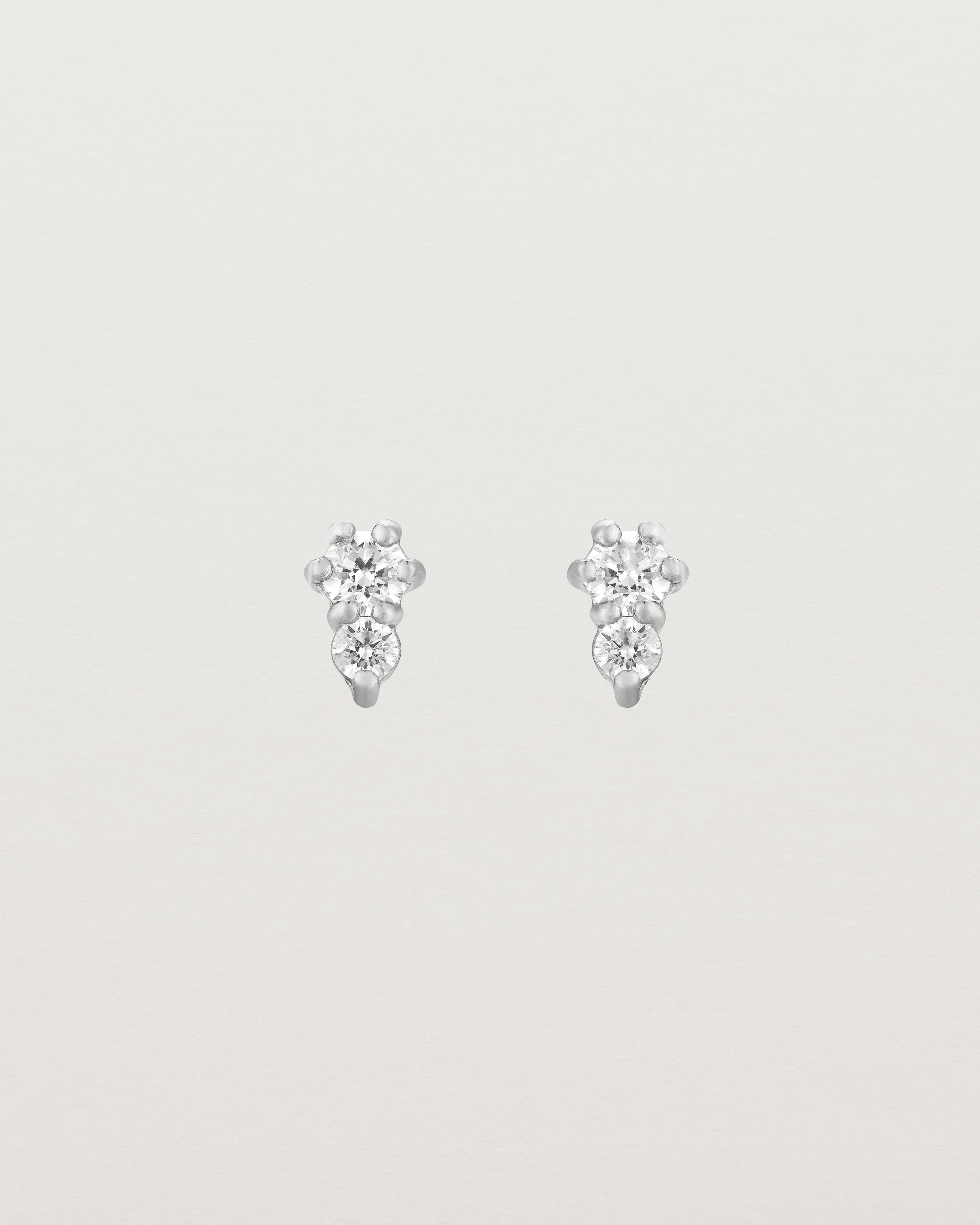 Front facing deep etched image of a pair of white gold earrings with diamonds.