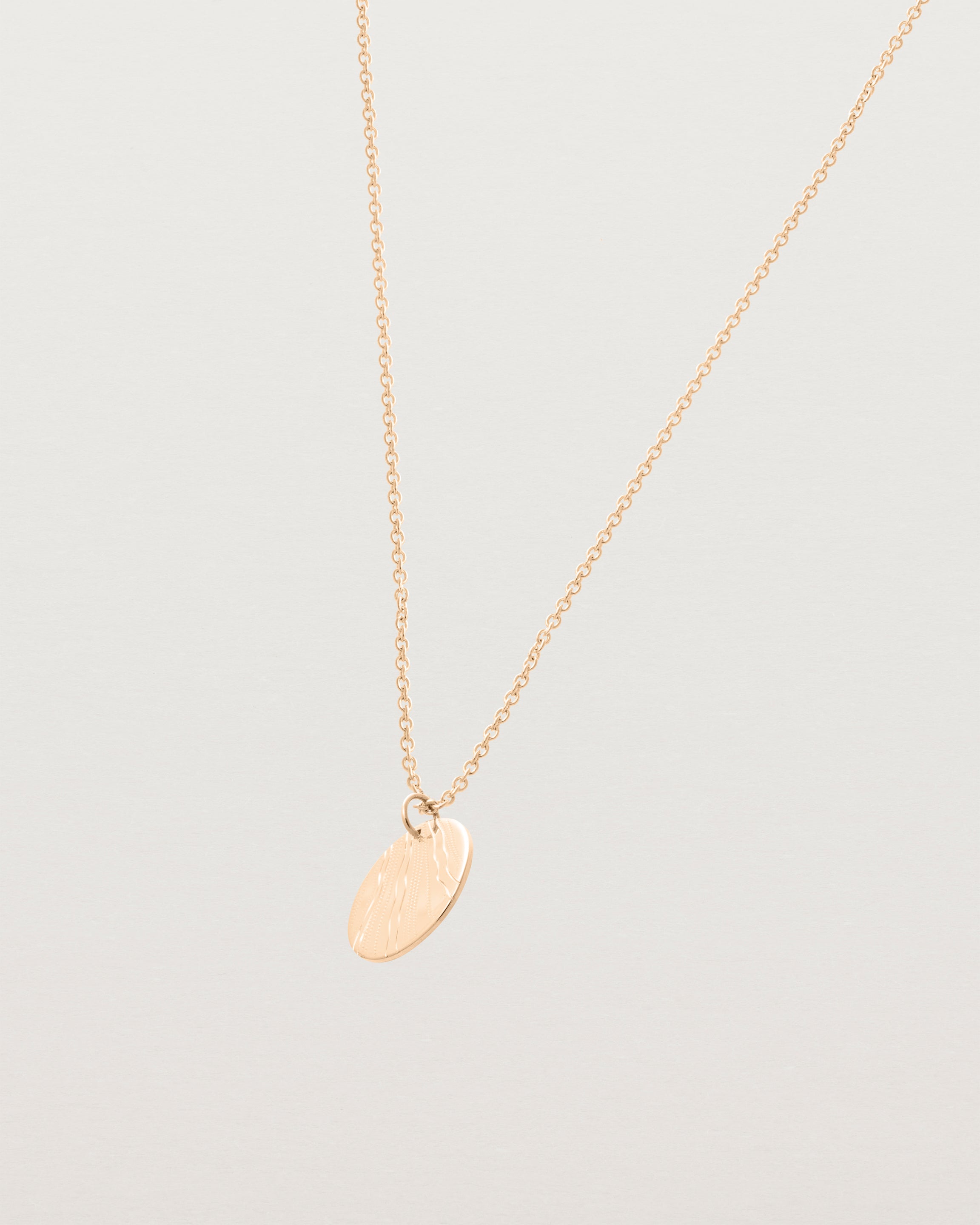 An engraved rose gold pendant