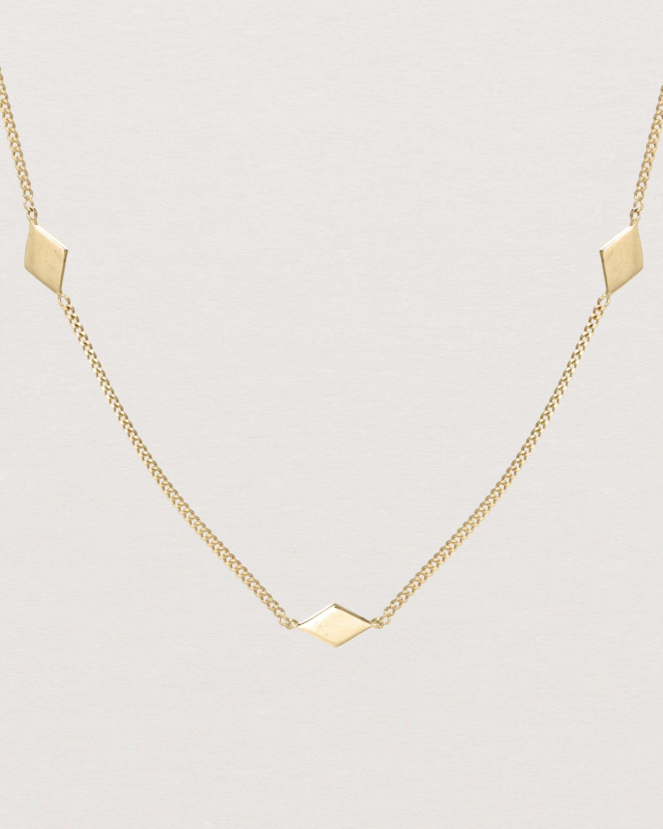 Close up view of the Nuna Charm Necklace in yellow gold.