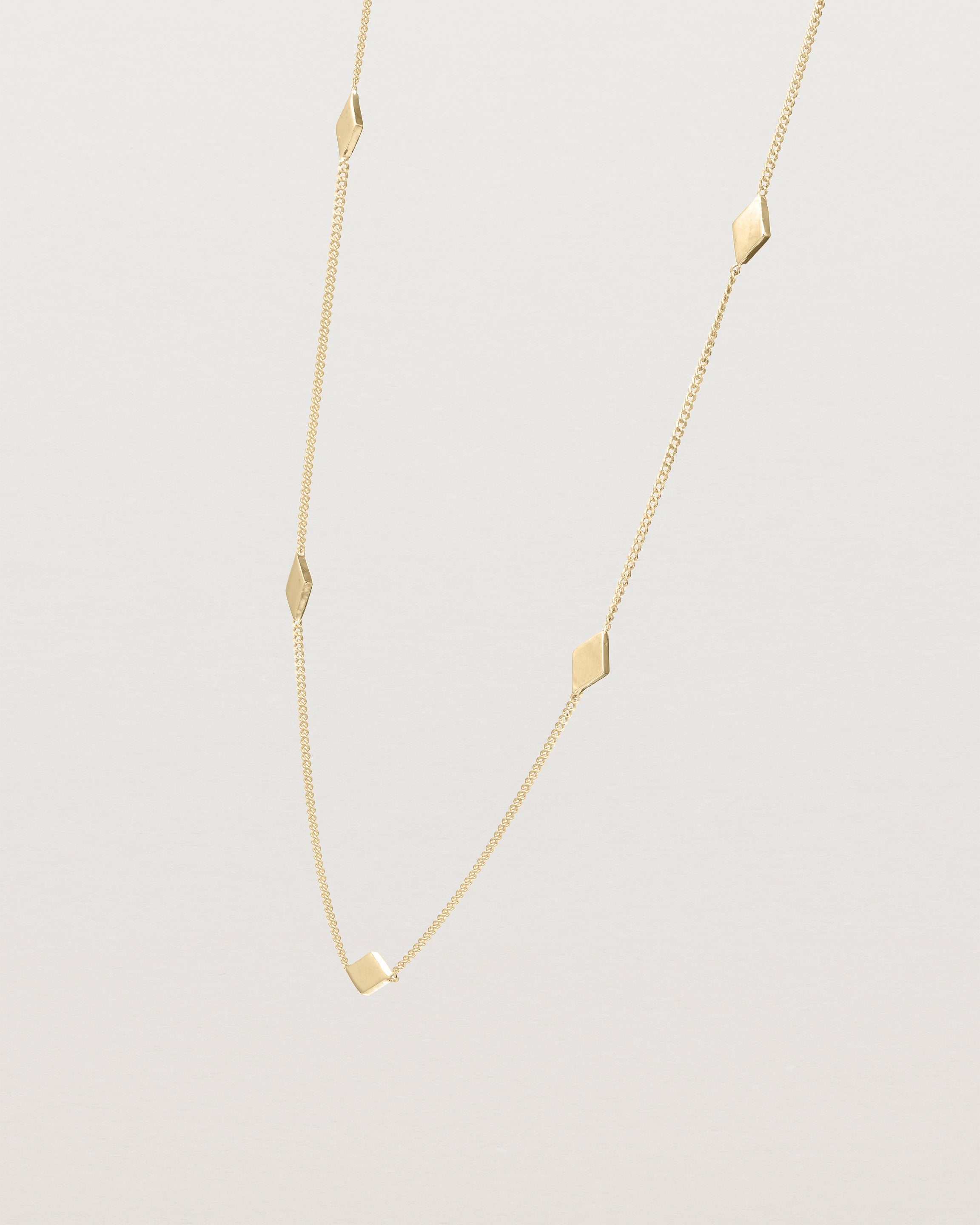 Angled view of the Nuna Charm Necklace in yellow gold.