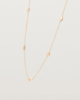 Angled view of the Nuna Charm Necklace in rose gold.