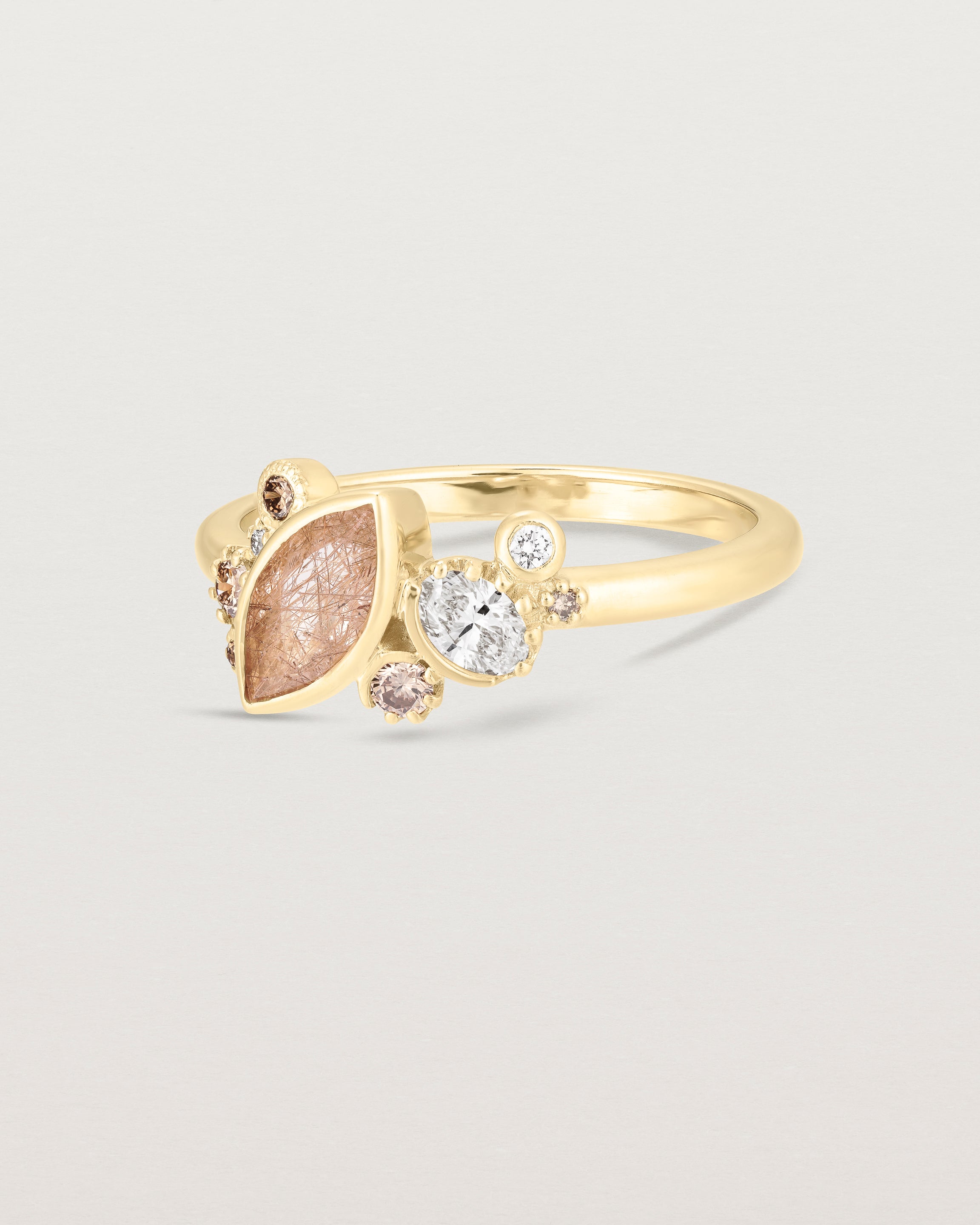 Product image of a yellow gold engagement ring with a rutilated quartz and diamonds, side view.