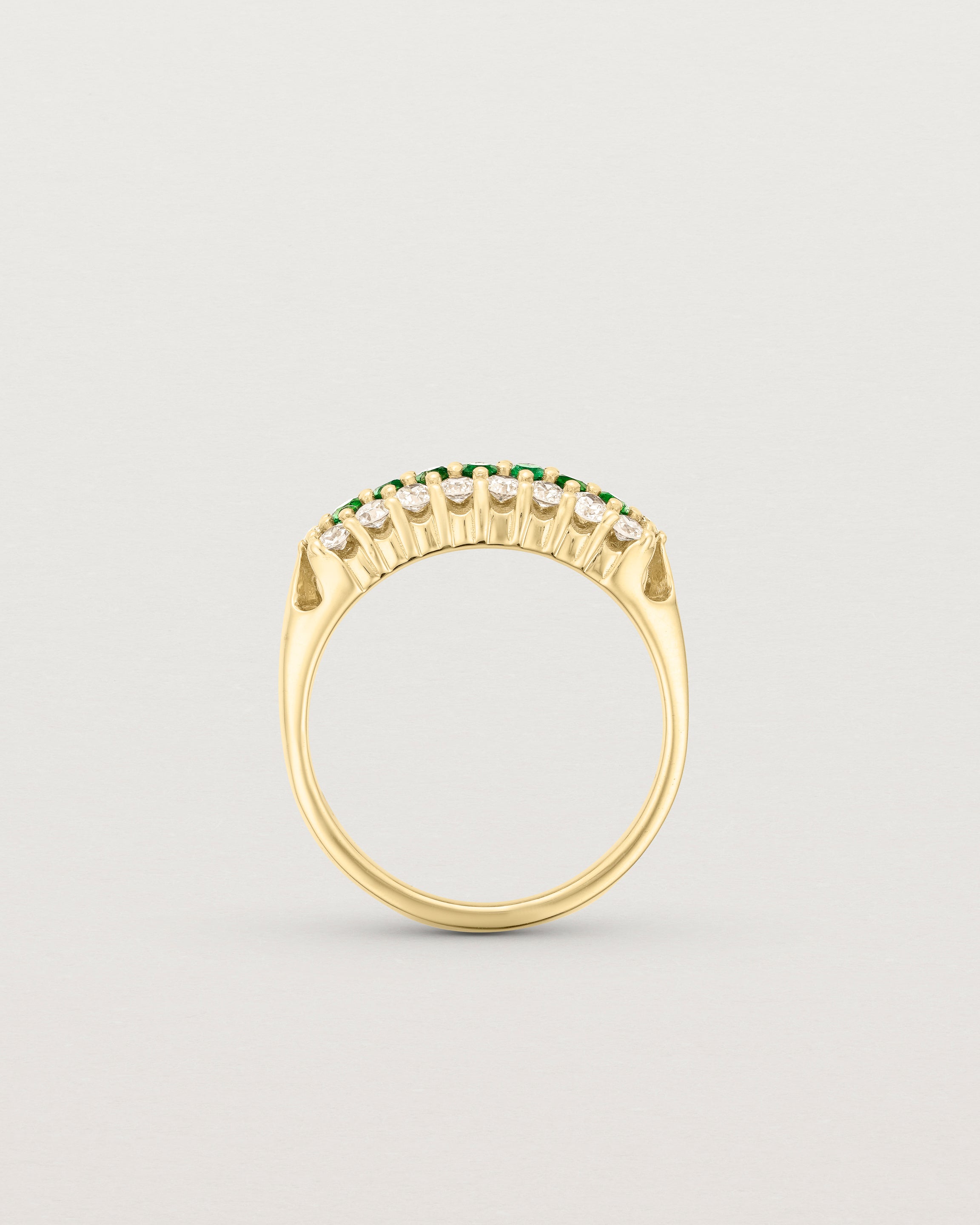 Standing deep etched image of a yellow gold vintage inspired wrap ring with seven green emeralds and a graduation of 18 old cut diamonds.
