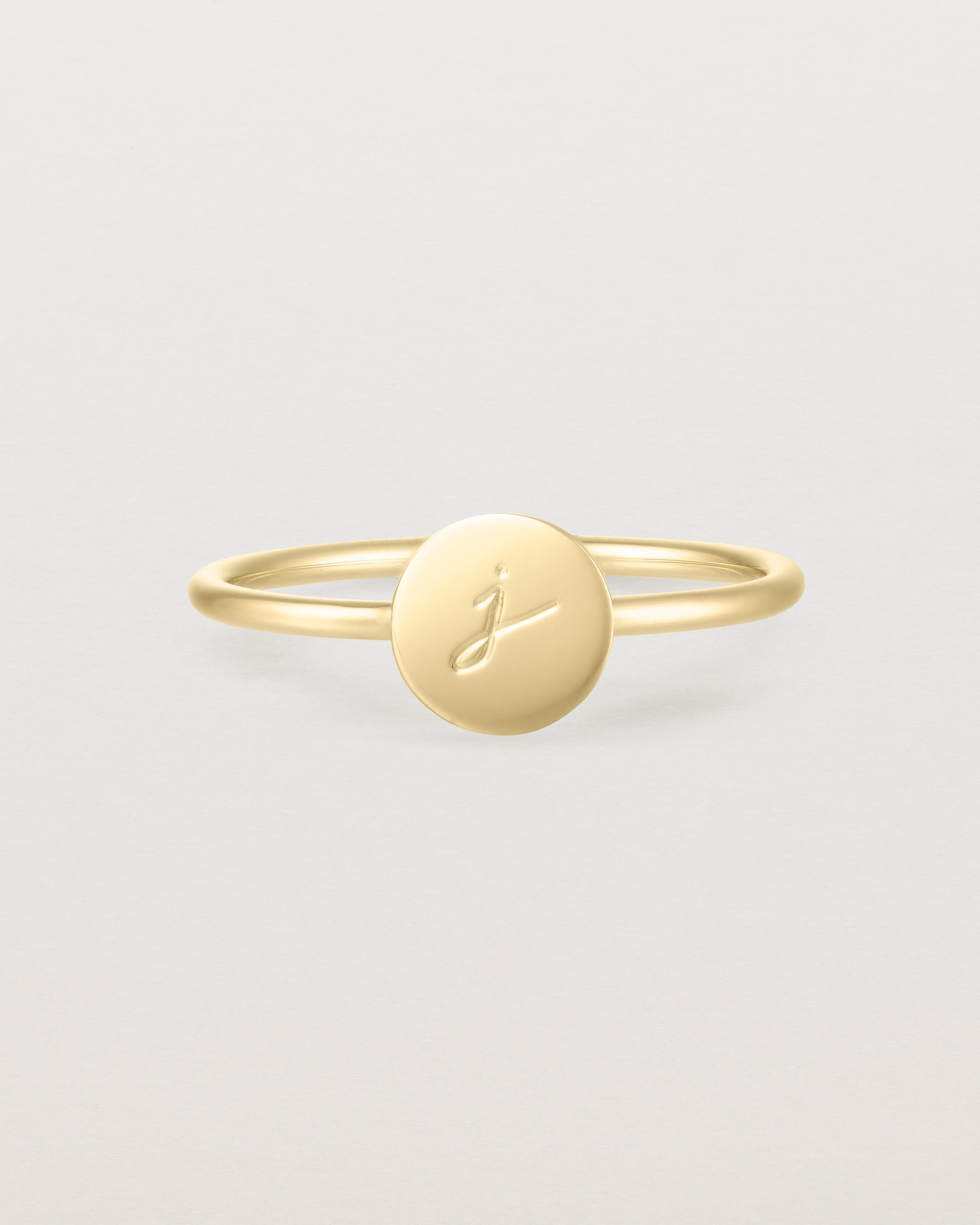 Front view of a yellow gold ring featuring a disc with the letter j engraved