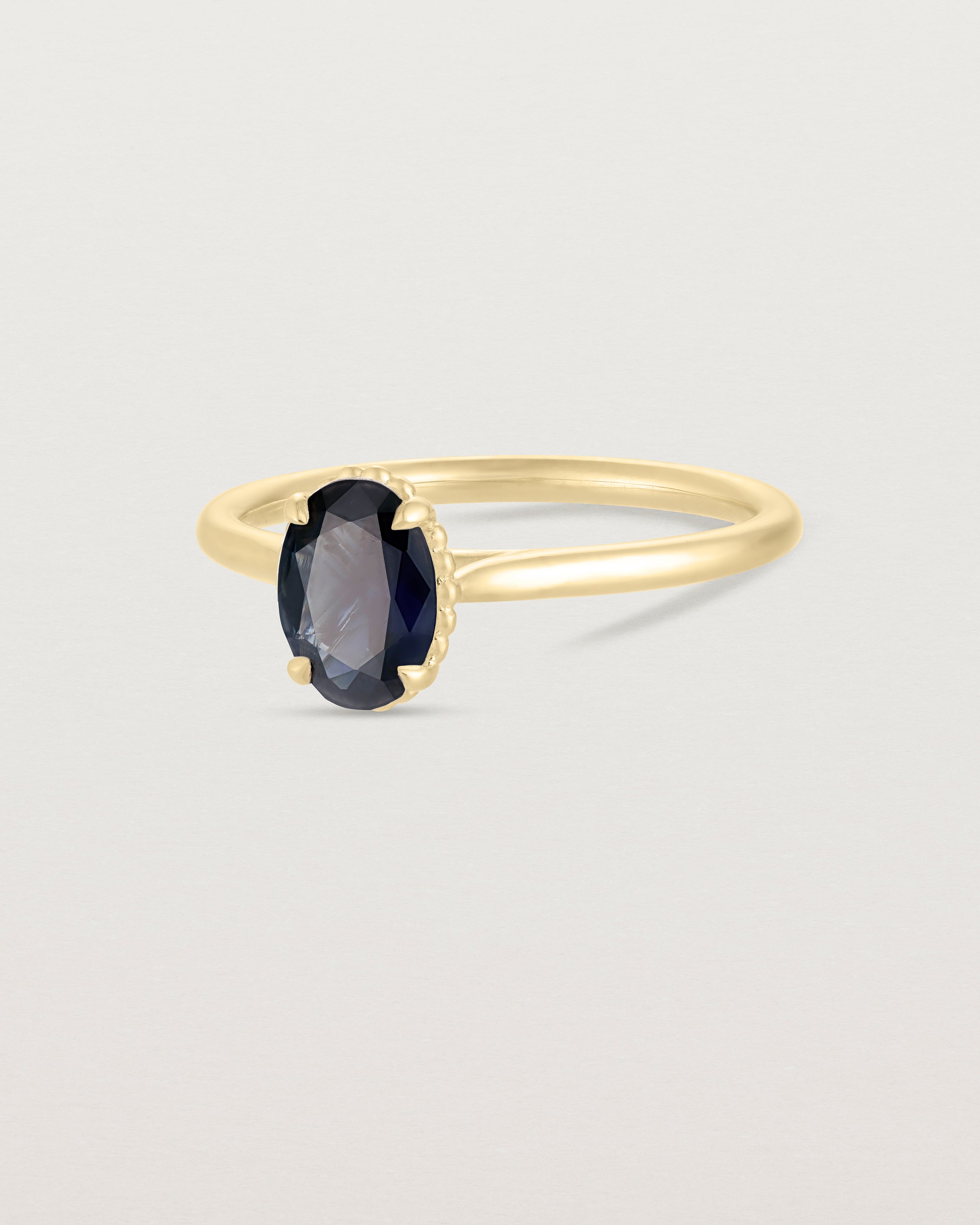 A side view of the Thea Oval Solitaire with a deep blue Australian Sapphire in Yellow Gold