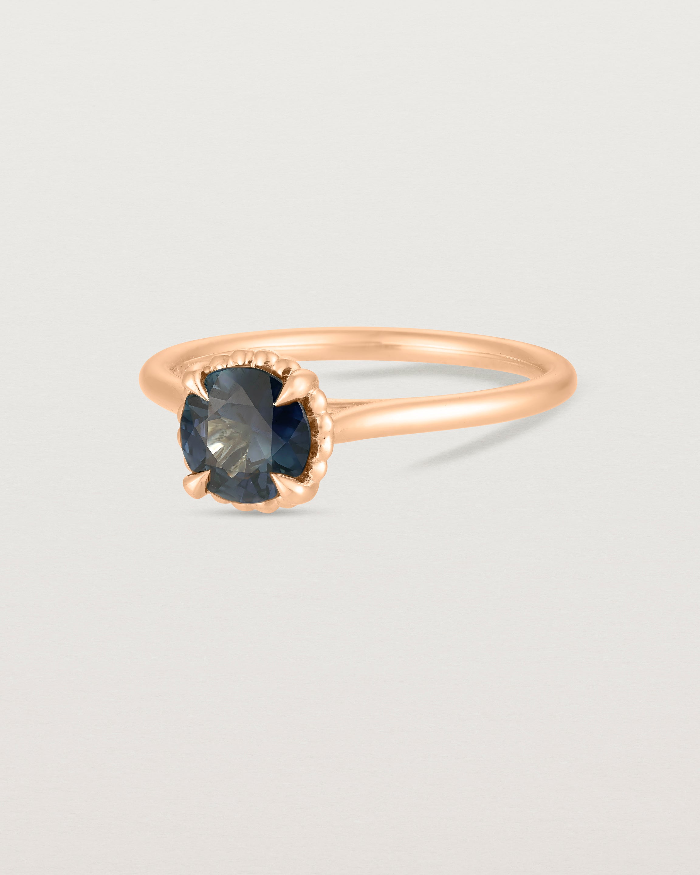 A side view of the Thea Round Solitaire with a deep blue Australian Sapphire in Rose Gold