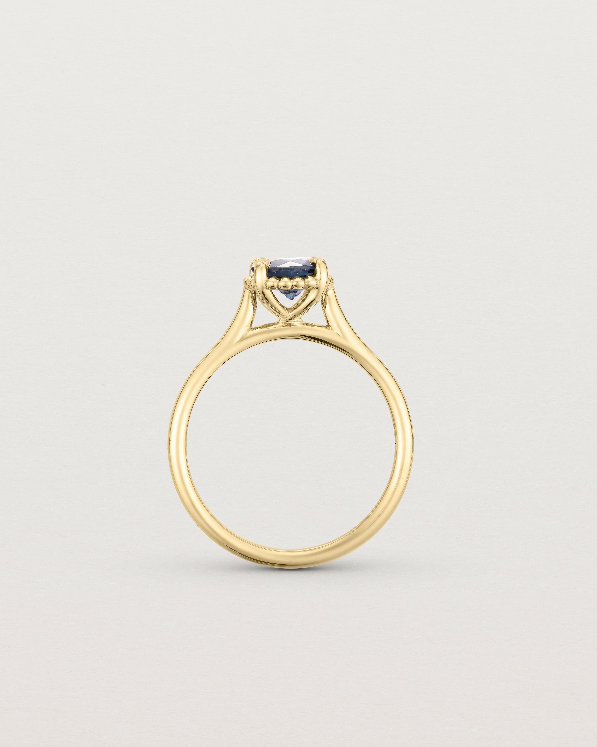 A side profile of the the Thea Round Solitaire with a deep blue Australian Sapphire in Yellow Gold