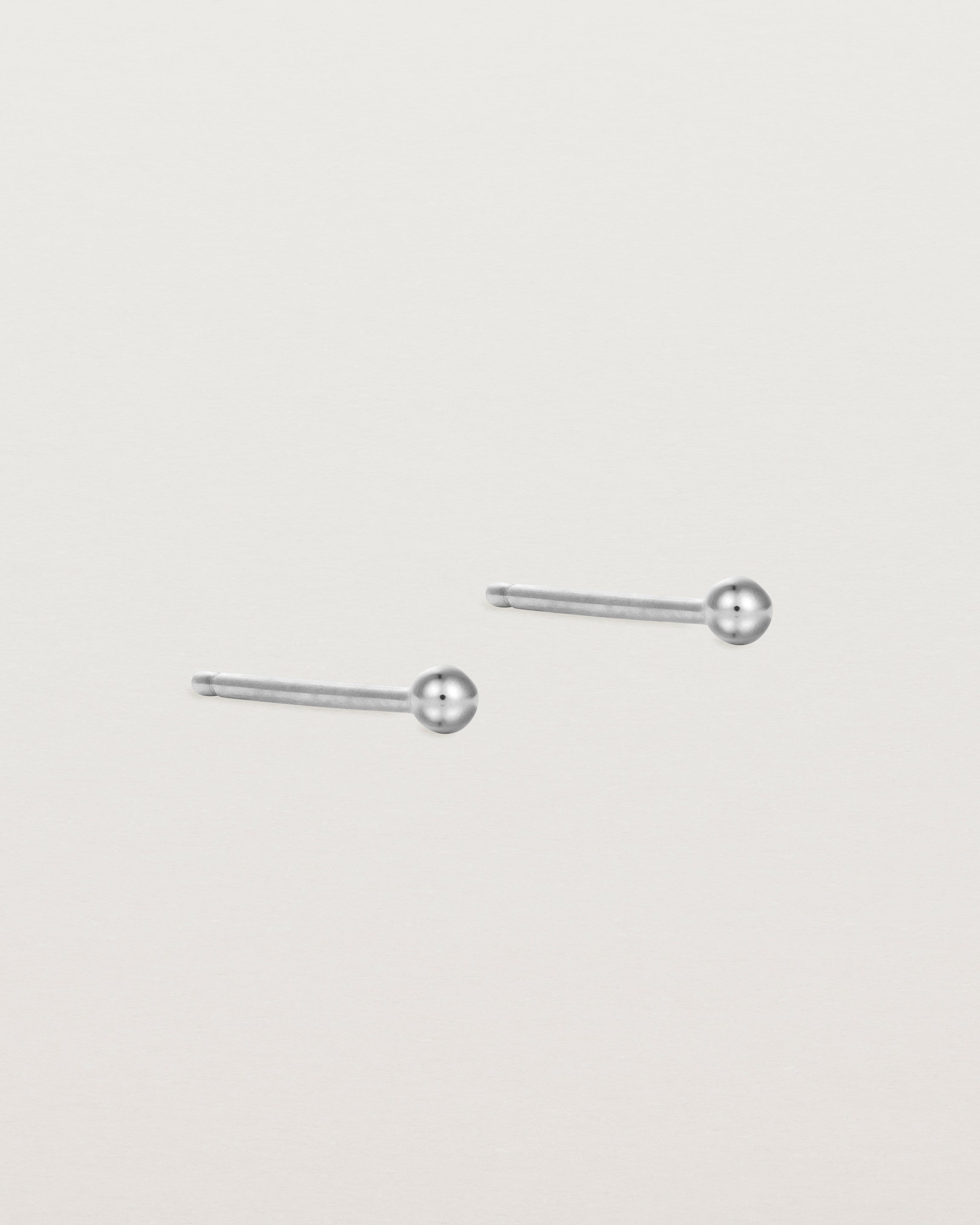 A pair of tiny sterling silver studs featuring a round ball