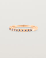 A fine rose gold wedding ring with thirteen blue sapphires