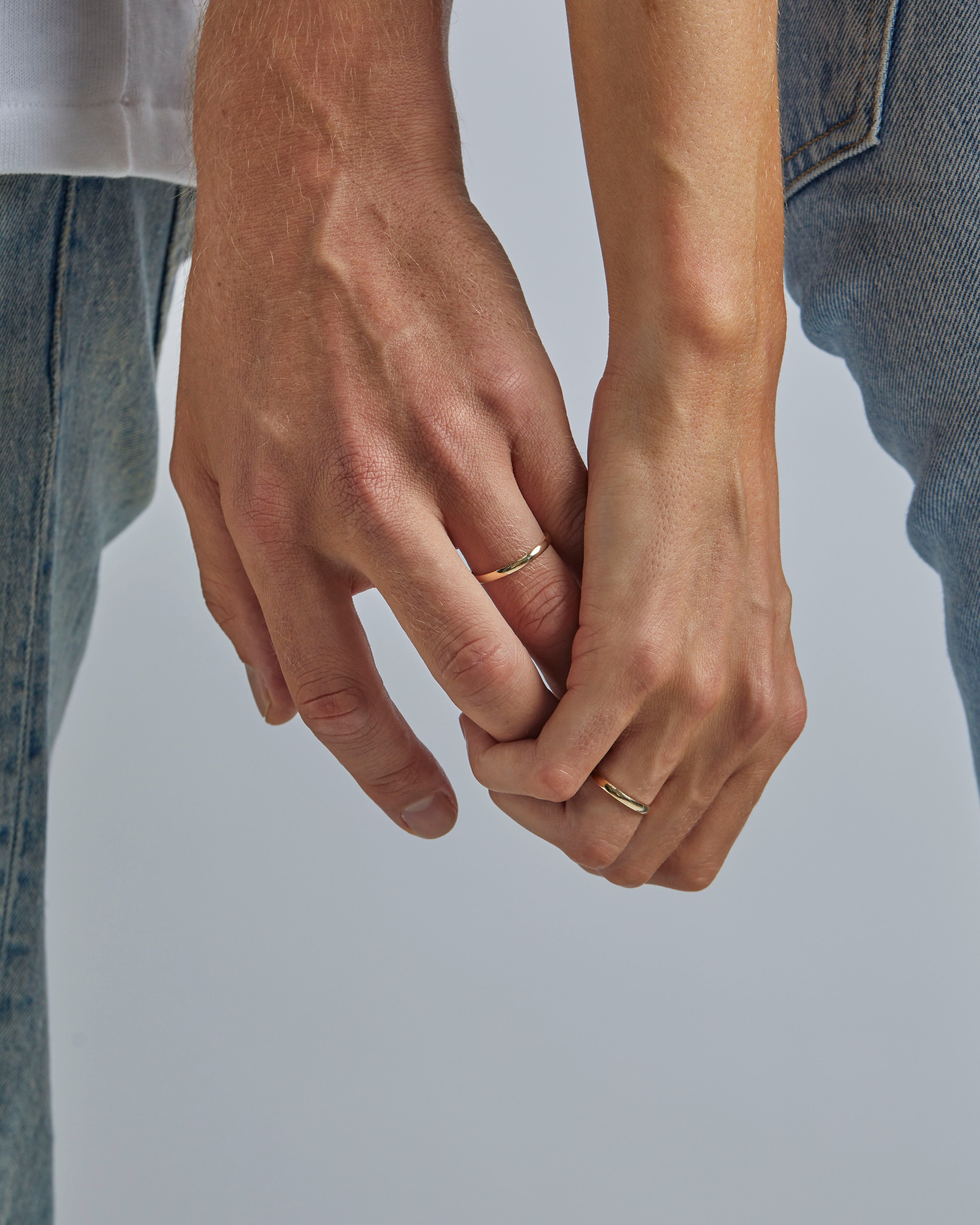 A male and female model wear the 2mm classic wedding band in yellow gold