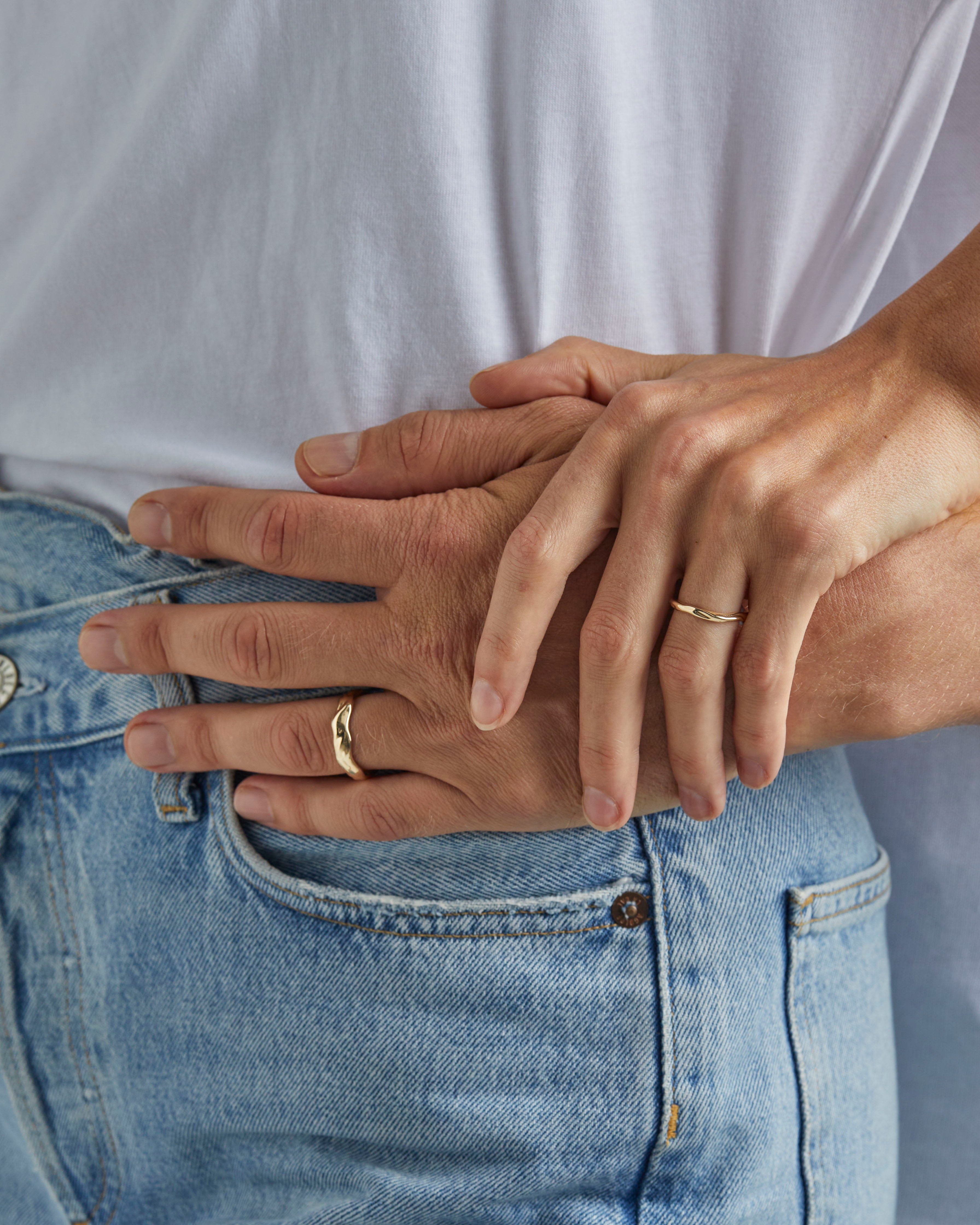 A female wears the 2mm organic wedding ring and male model wears the 6mm organic wedding ring, in yellow gold